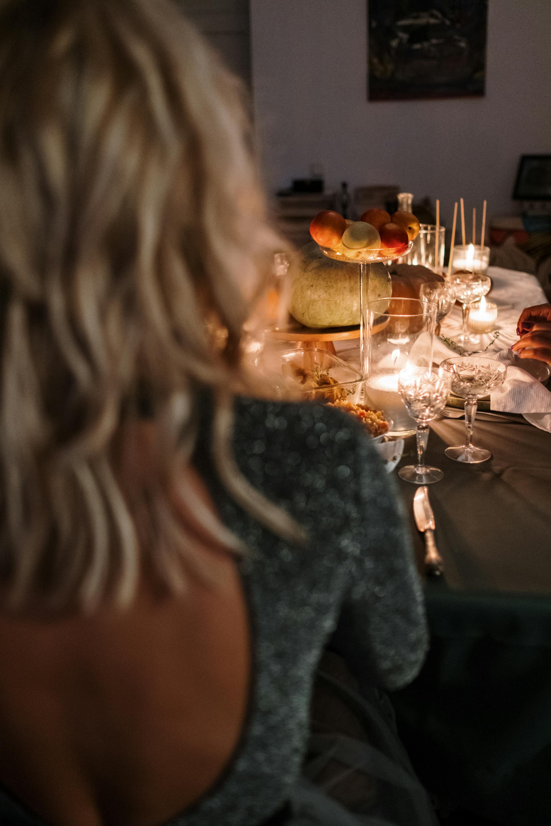 A woman in a backless dress sitting at a dinner table | Source: Pexels