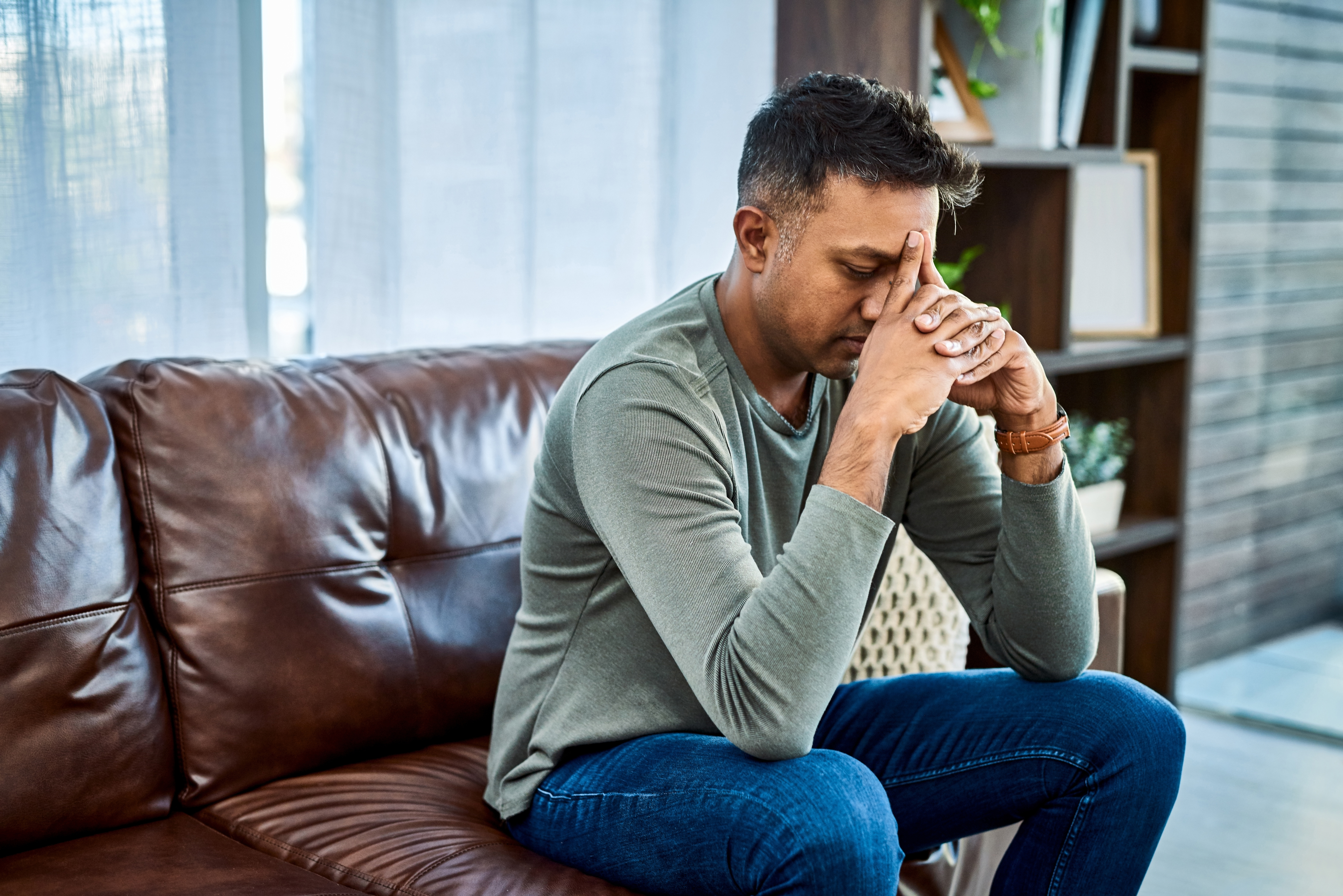 An upset man sitting on a sofa | Source: Shutterstock