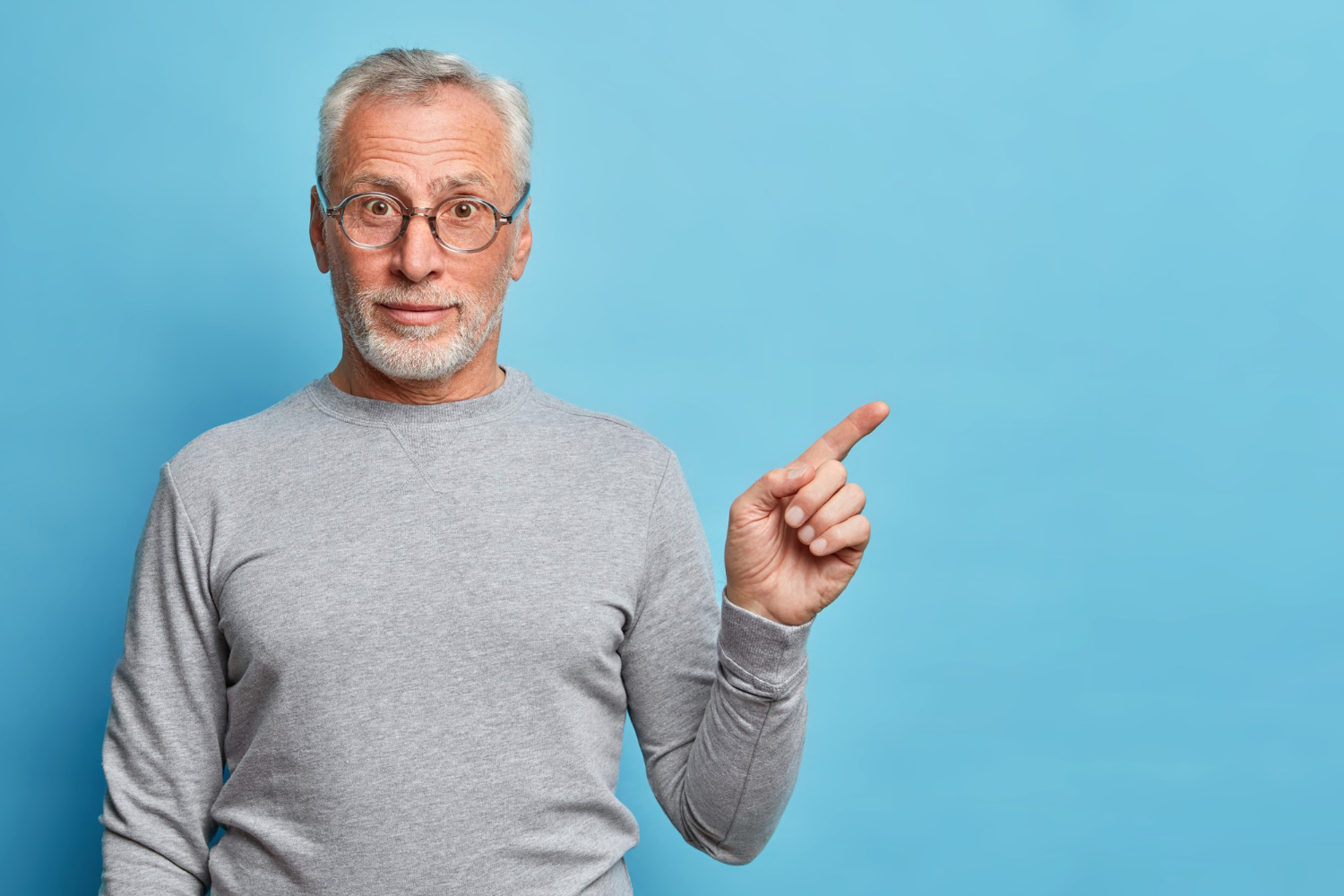 A smiling senior man pointing his finger | Source: Freepik