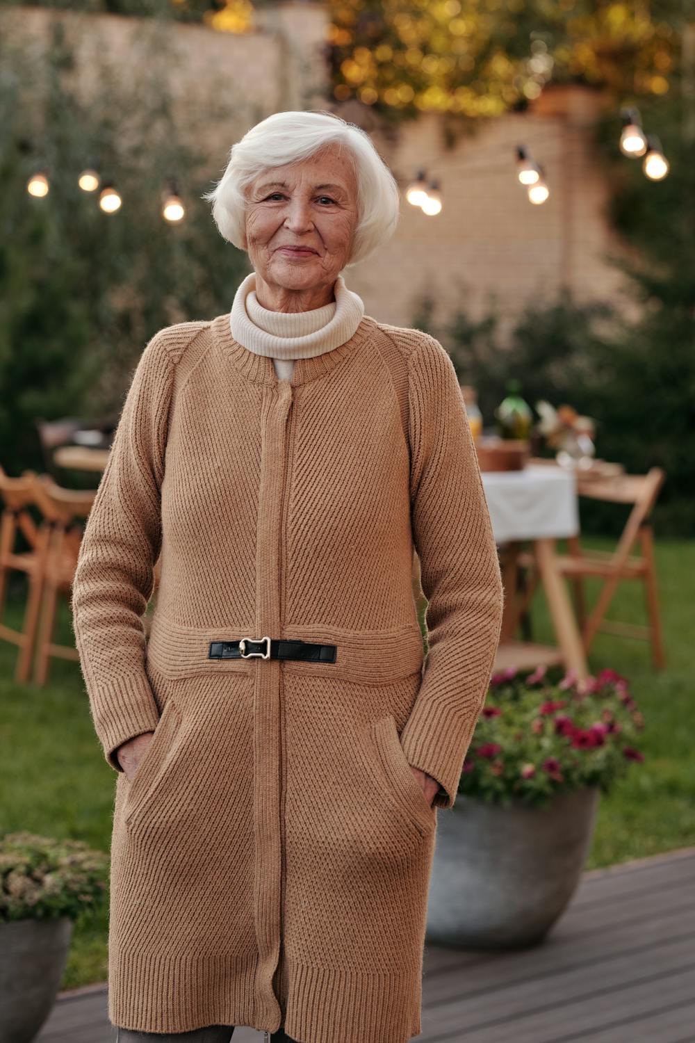 Une femme souriante sur son porche ⏐ ​​Source : Pexels