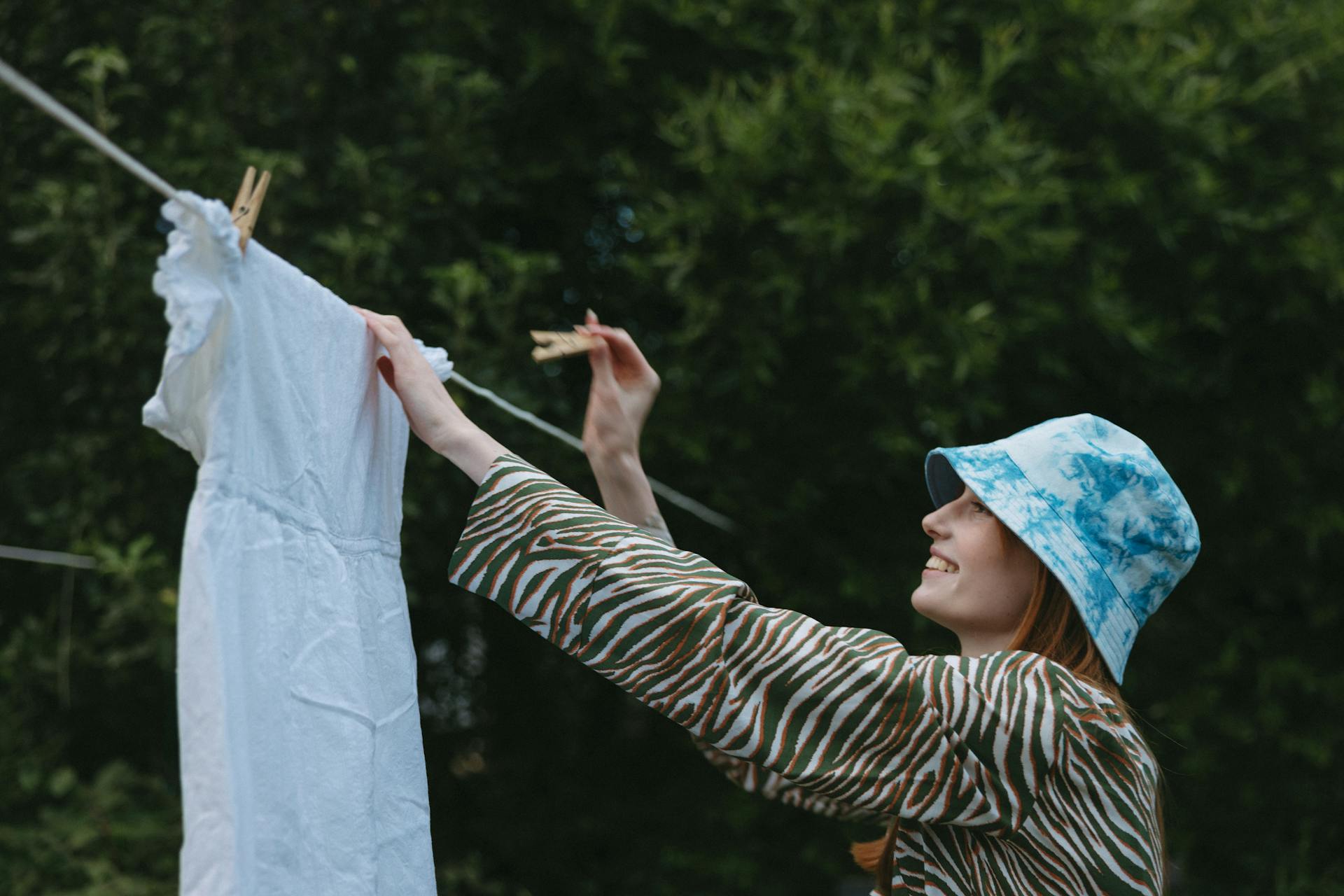 A smiling woman hanging a dress on a clothesline | Source: Pexels