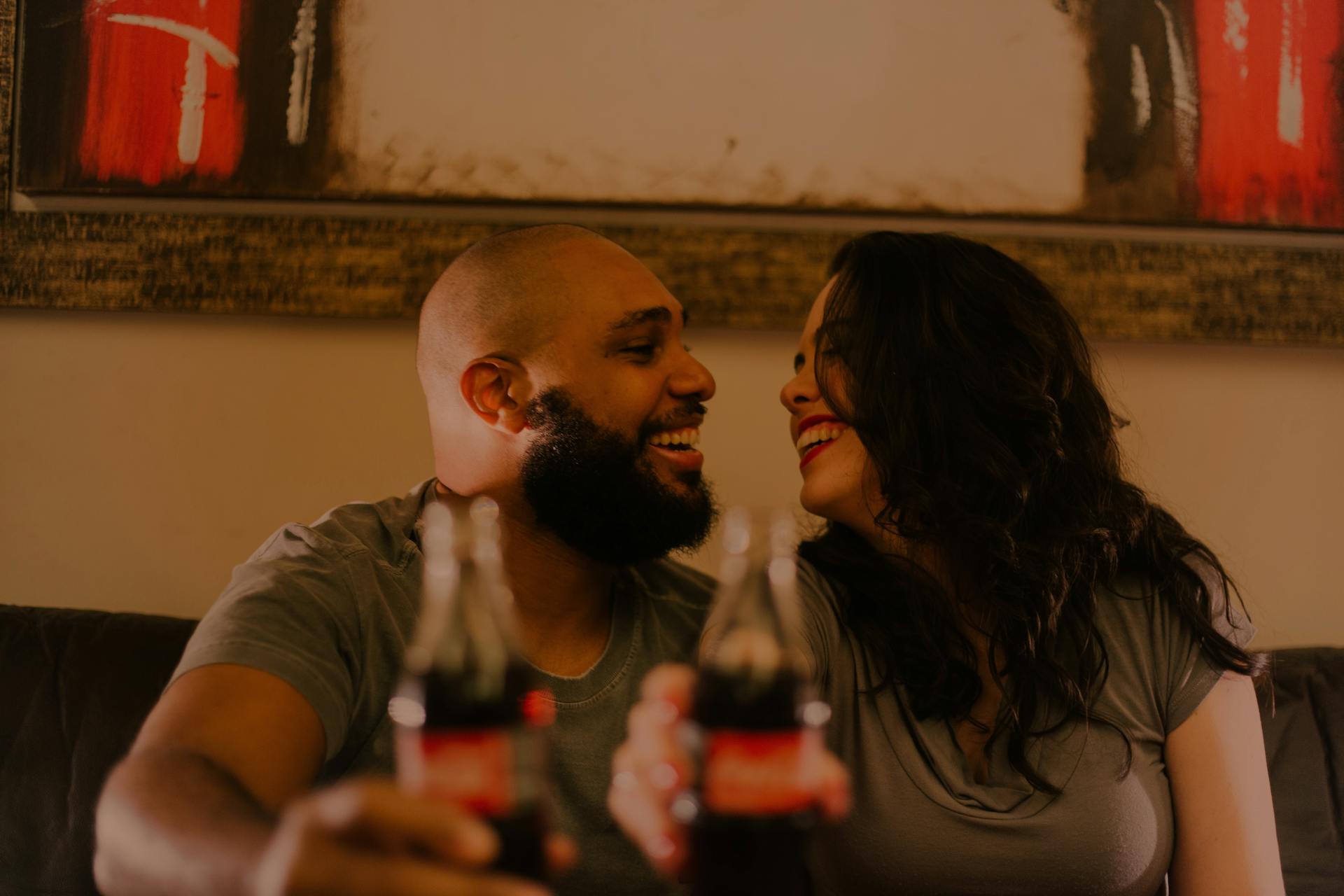 A couple laugh while holding their soft drink bottles | Source: Pexels