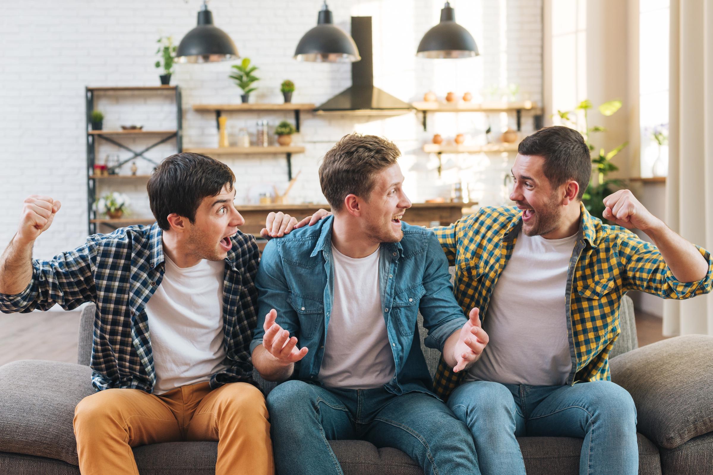 Three men sitting on a sofa and shouting | Source: Freepik