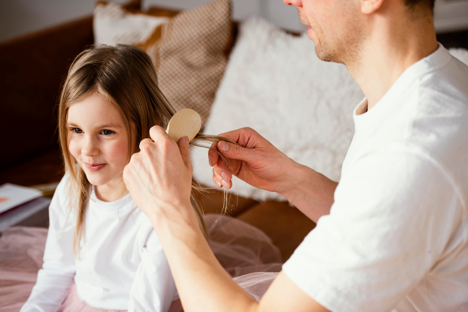 A man brushing his daughter's hair | Source: Freepik