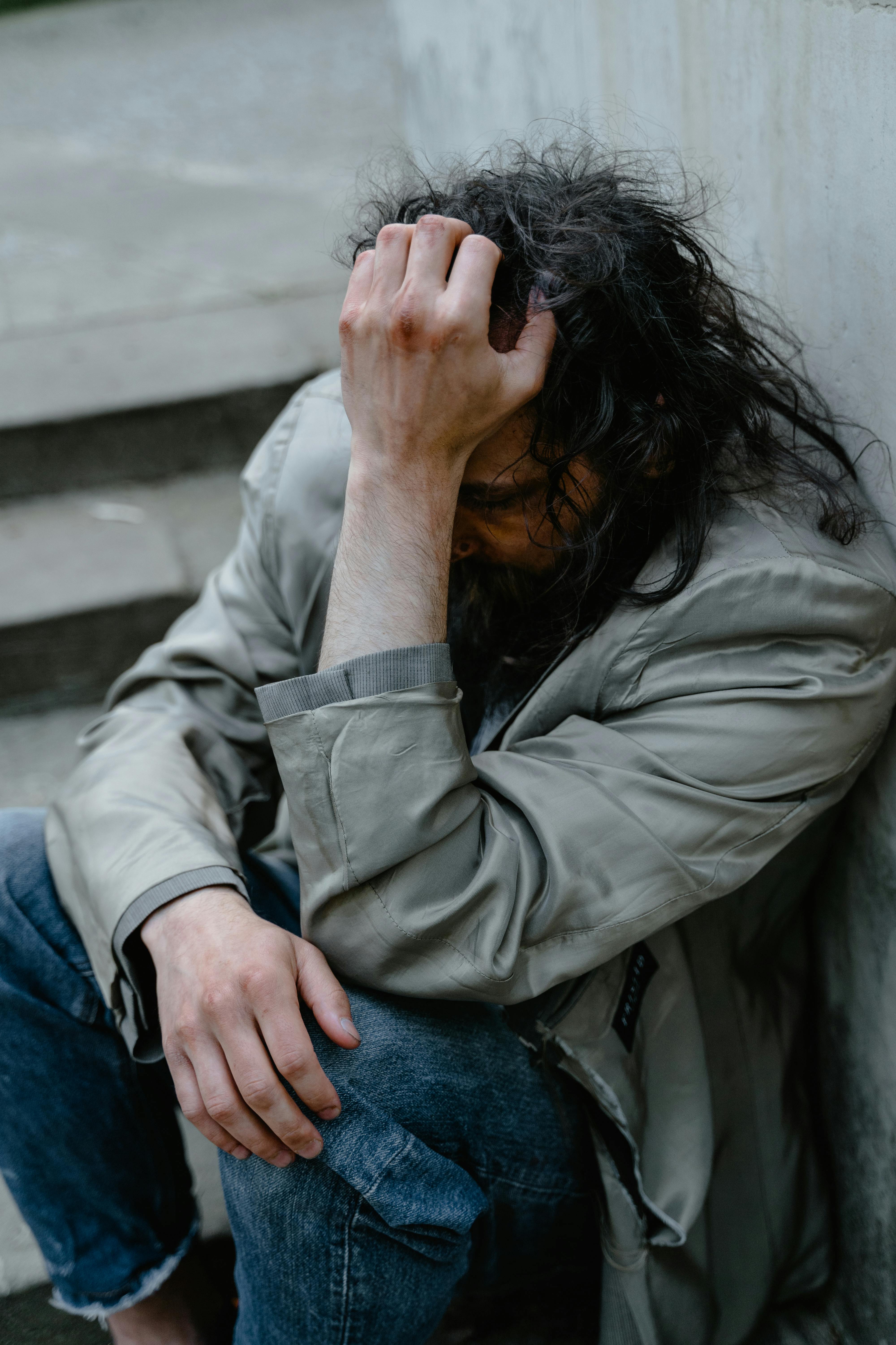 A miserable man sitting against a wall | Source: Pexels