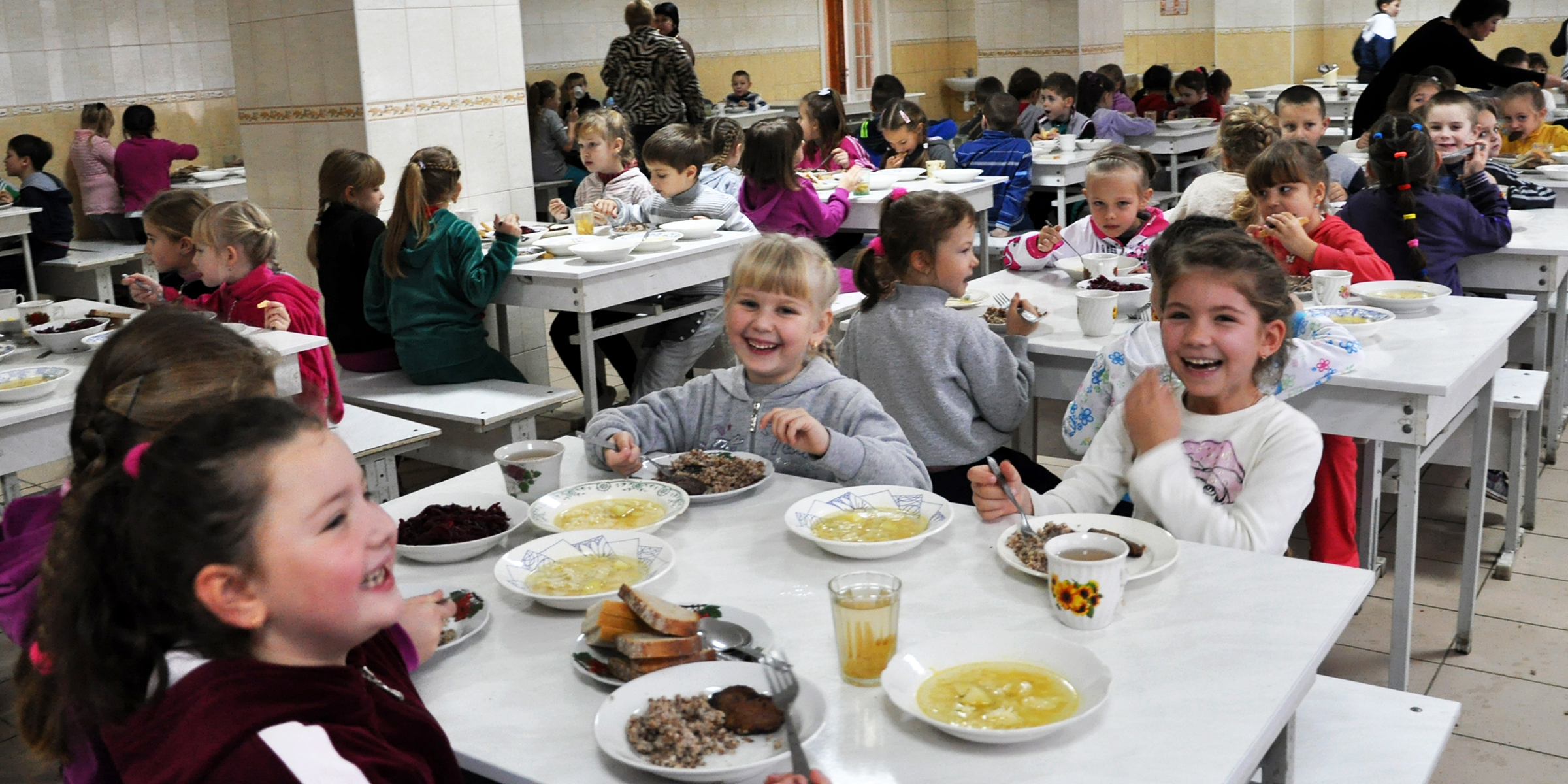 Children sitting in a cafeteria | Source: Shutterstock