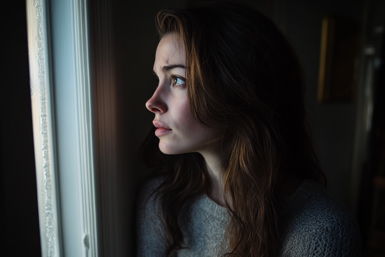 A sad woman staring out a window | Source: Midjourney