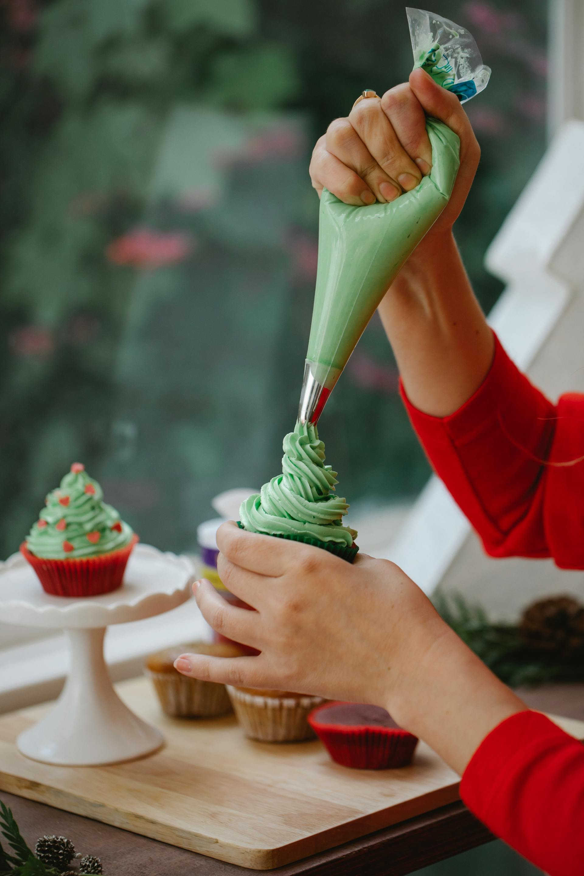 A closeup shot of a woman decorating a home-backed cupcake with cream | Source: Pexels