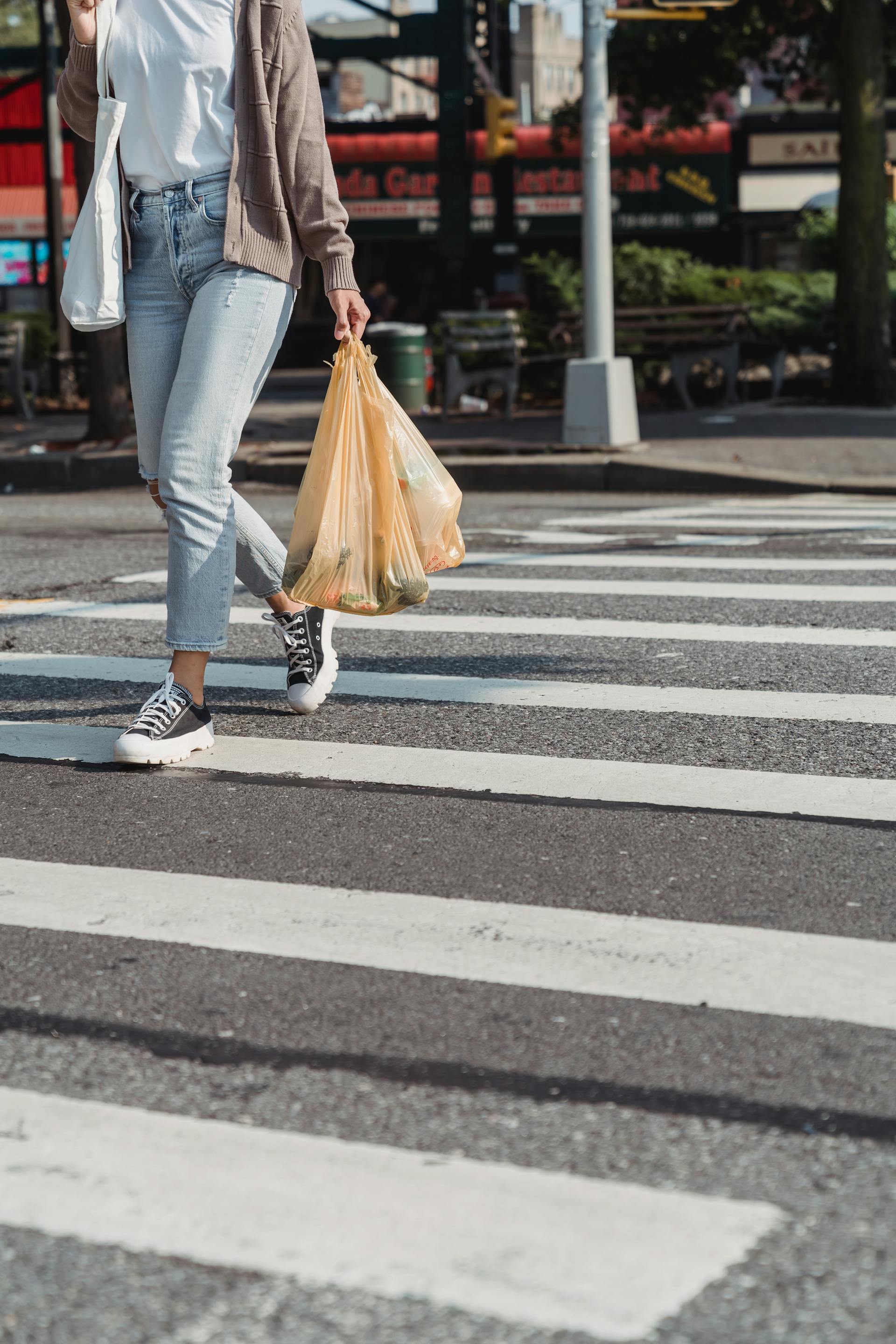 A woman walking on a zebra crossing holding grocery bags | Source: Pexels