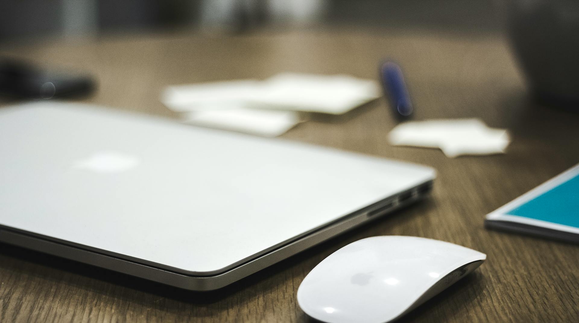 A laptop and a wireless mouse on the table | Source: Pexels