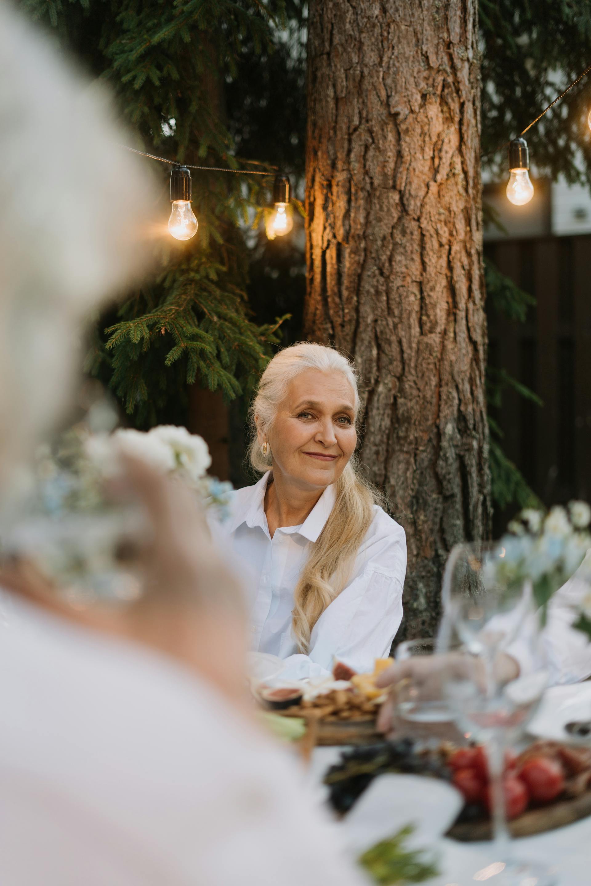 A mature woman with long, blonde hair smiling at a party | Source: Pexels