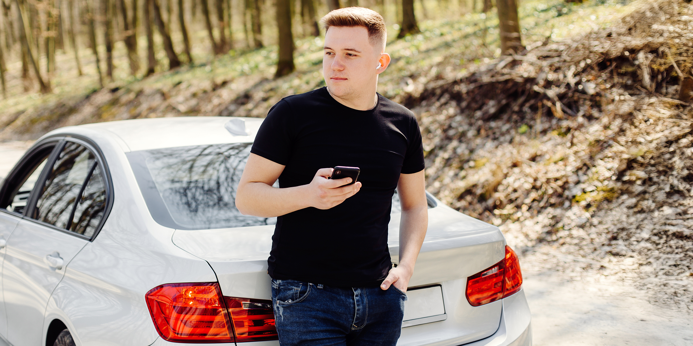 A man standing by a car and holding a phone | Source: Shutterstock