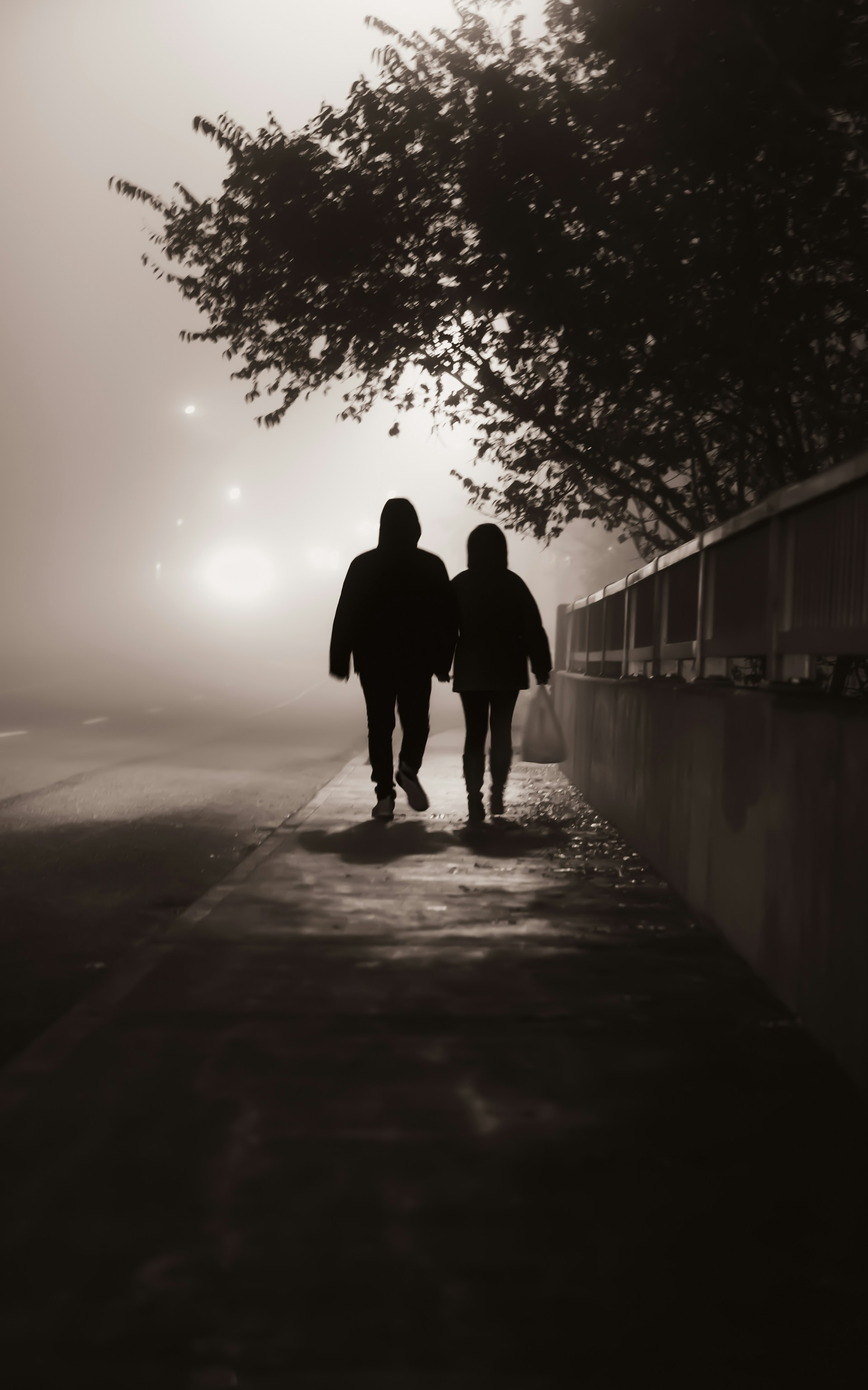 A couple walking on the sidewalk on a misty evening | Source: Unsplash