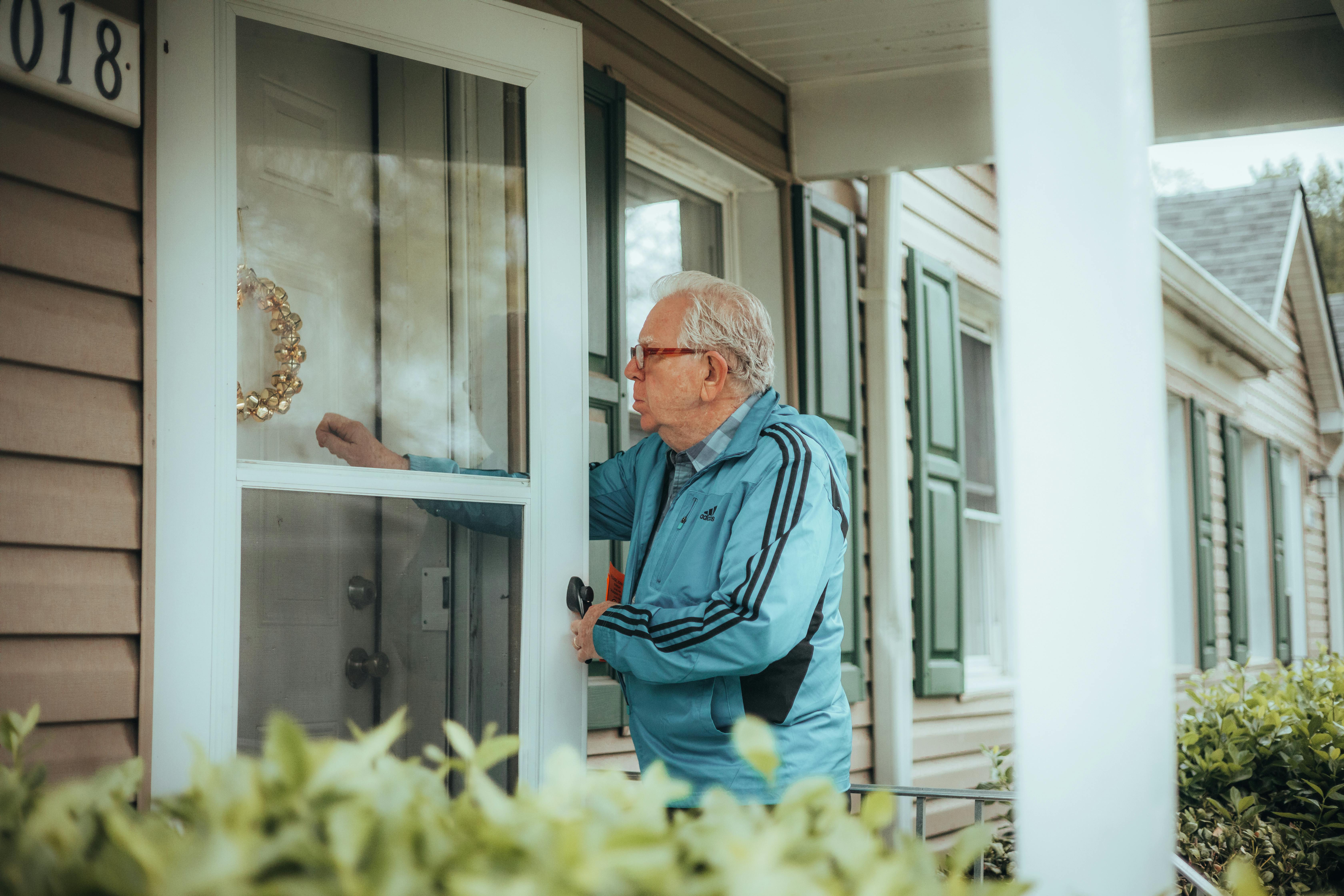 Homem idoso batendo na porta da frente de uma casa | Fonte: Pexels