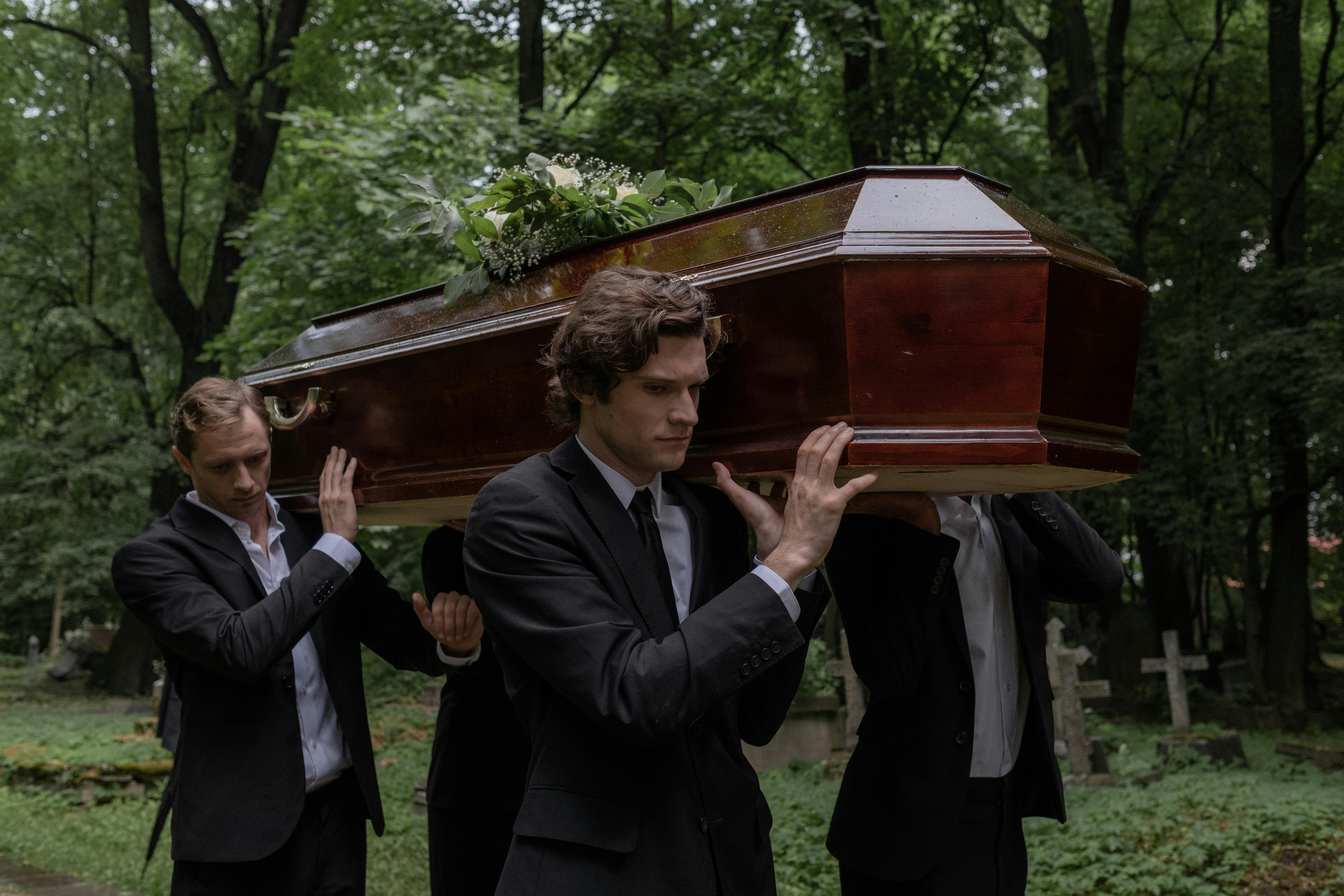 Men carrying a coffin in a graveyard | Source: Midjourney