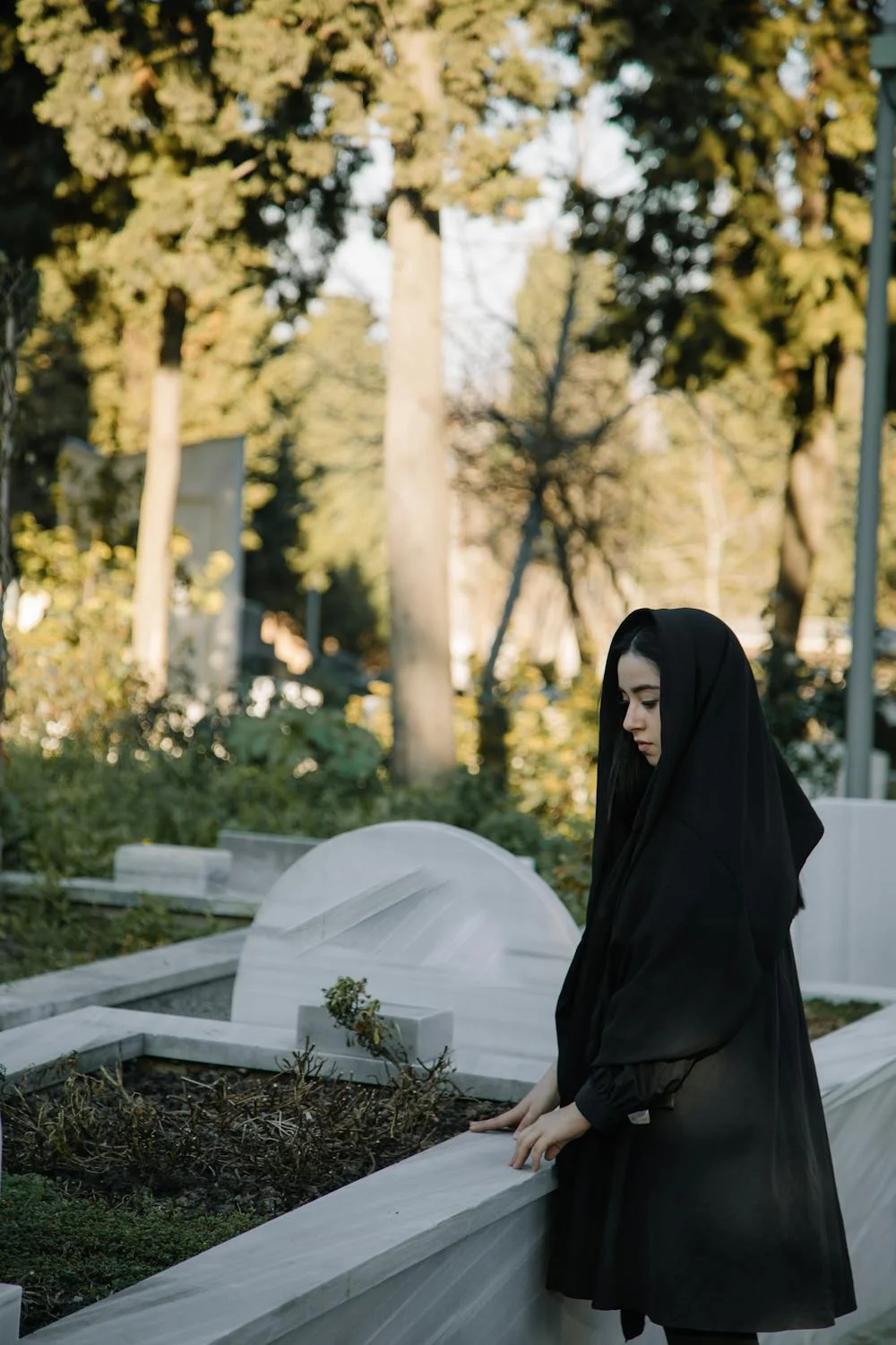 A woman in black at a cemetery ⏐ Source: Pexels