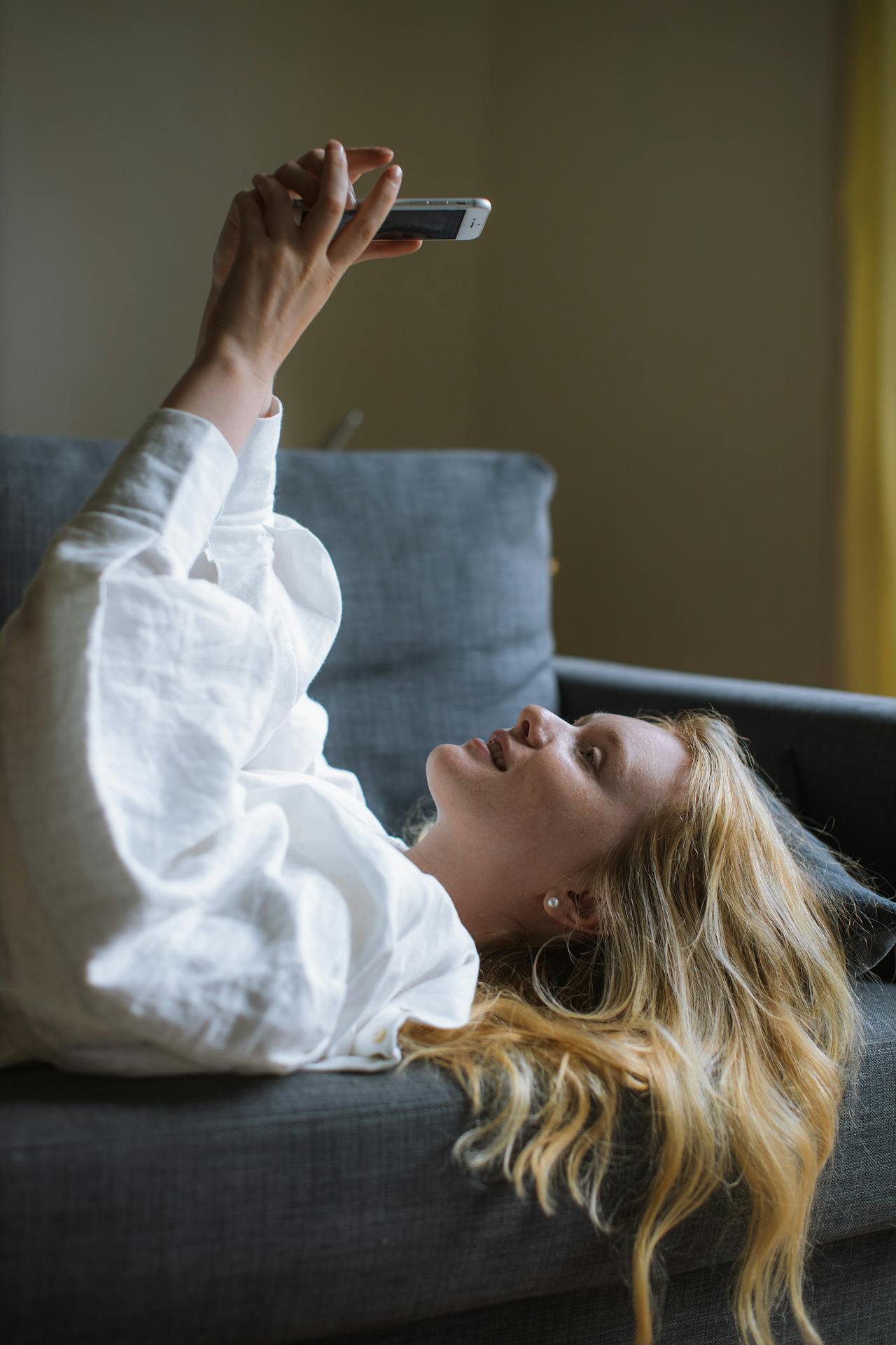 A woman lying on the couch and using her phone | Source: Pexels