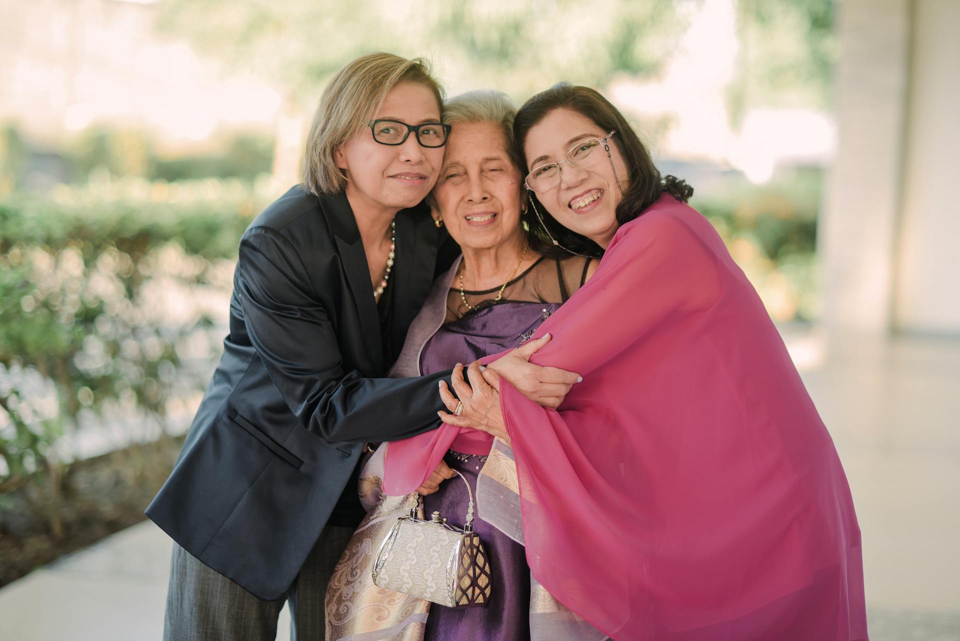 Three women smiling while they hug and pose for a photo | Source: Pexels