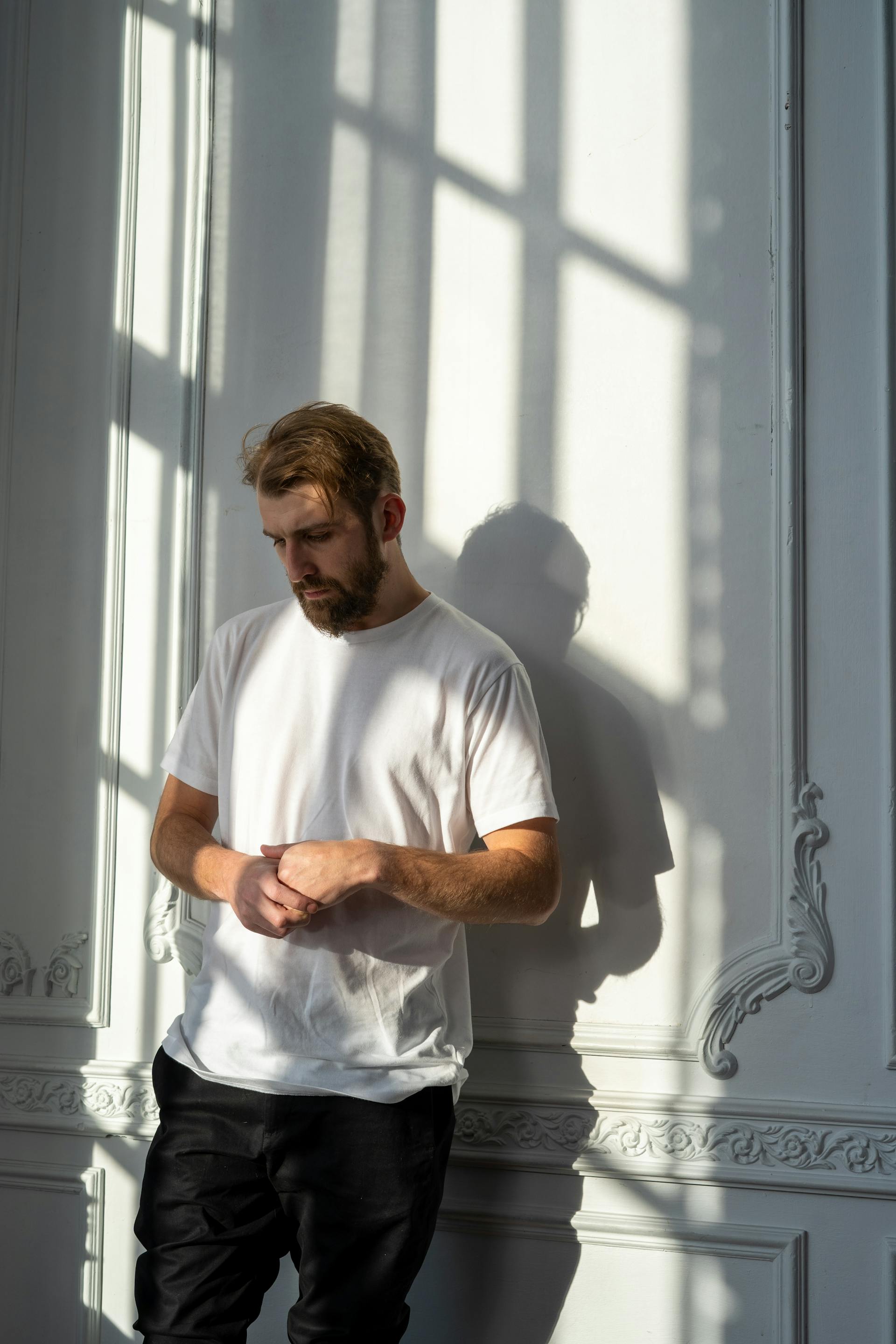 A sad man with eyes downcast standing near a wall | Source: Pexels