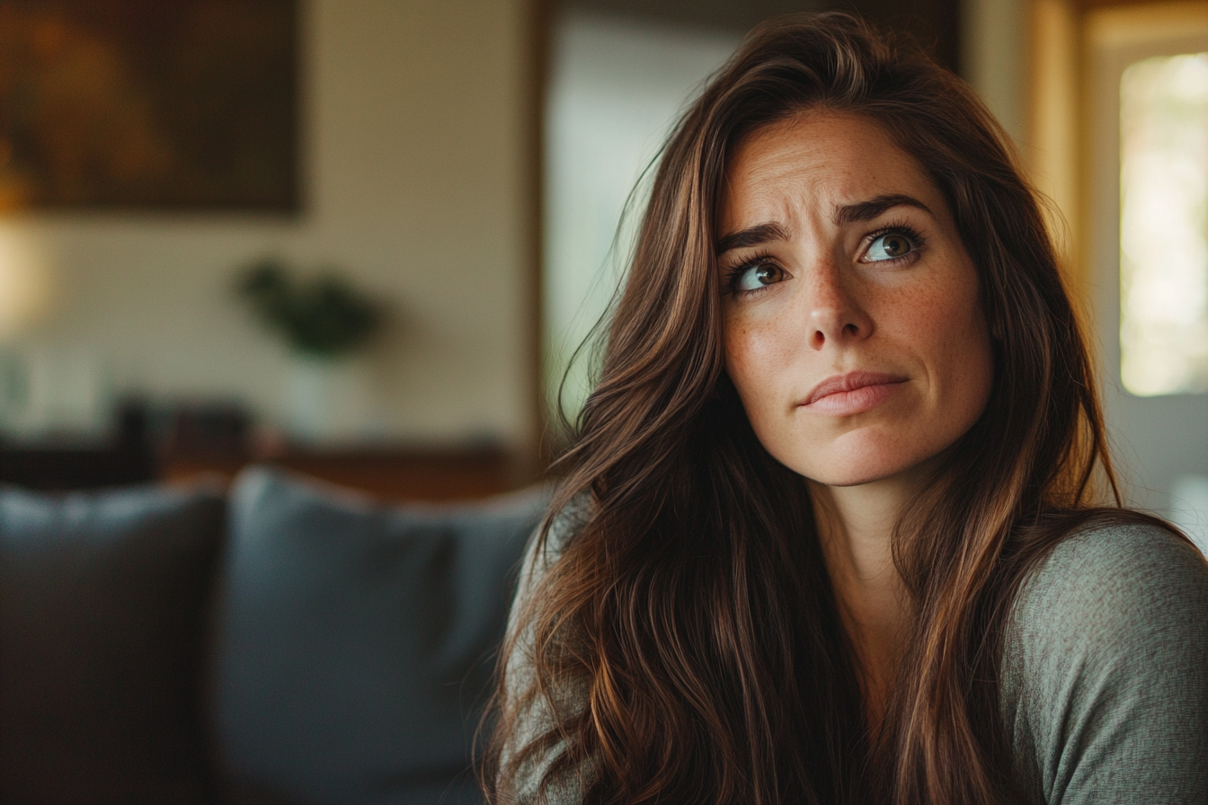 A thoughtful woman in a living room | Source: Midjourney