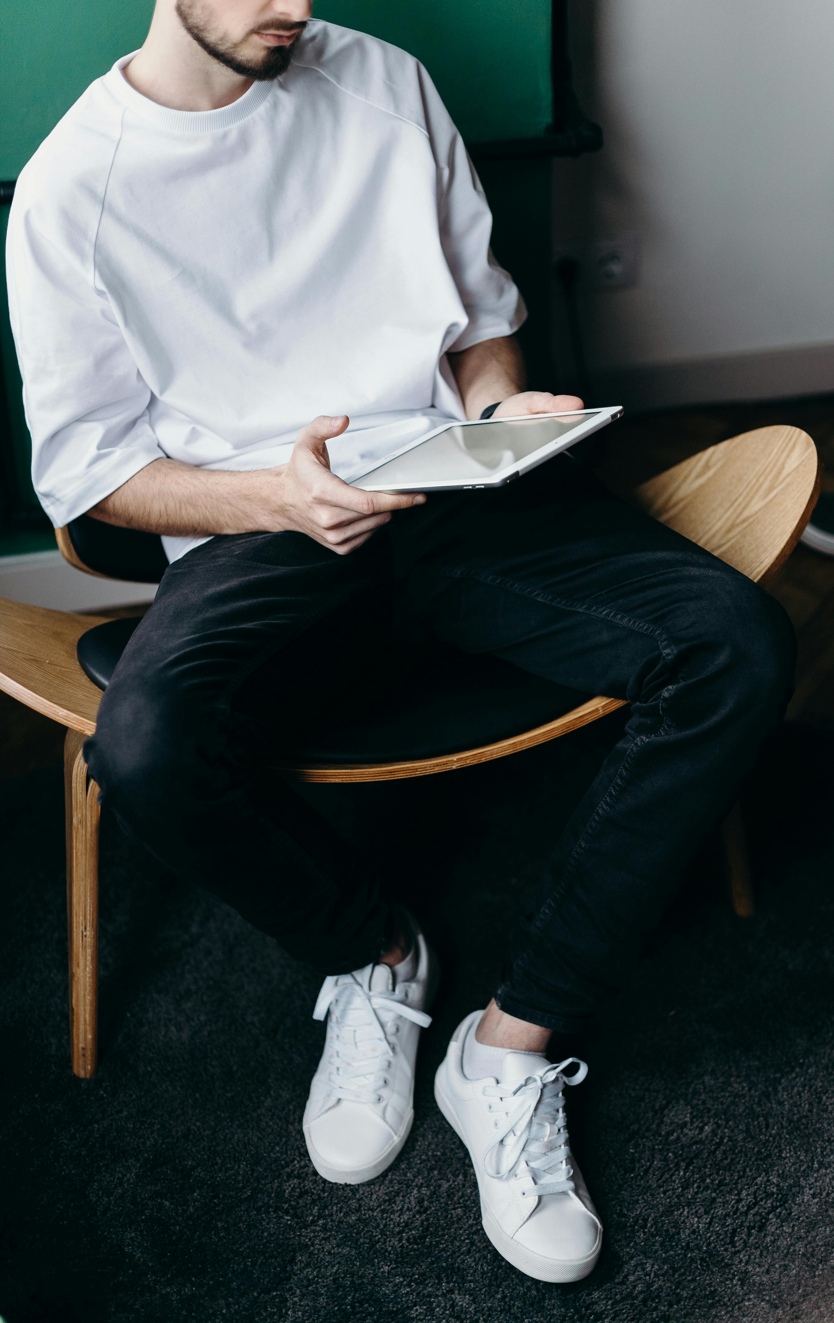 Man in white shirt and black pants using a tablet | Source: Pexels