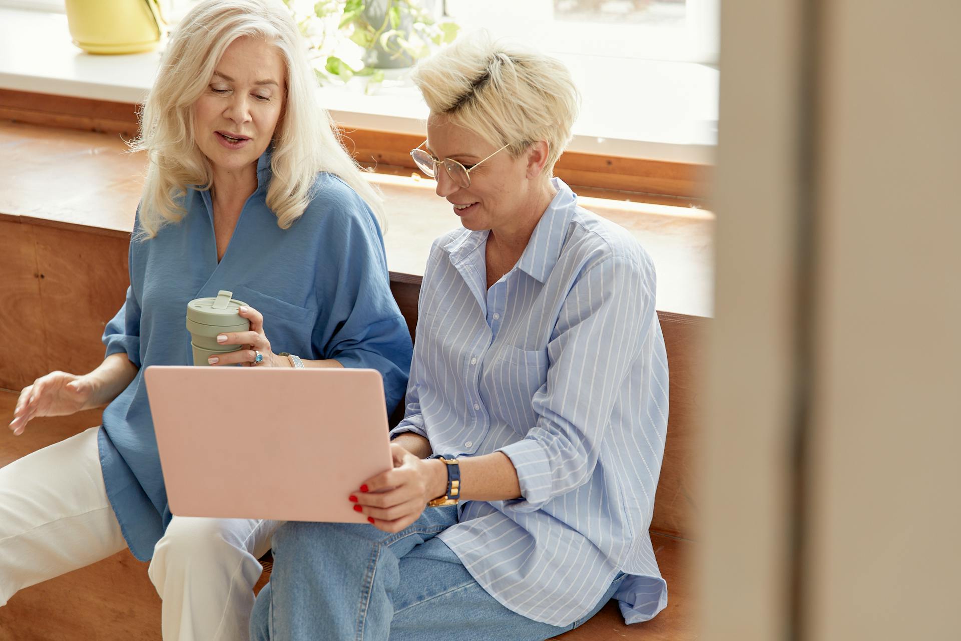 Two senior women talking while looking at a laptop screen | Source: Pexels