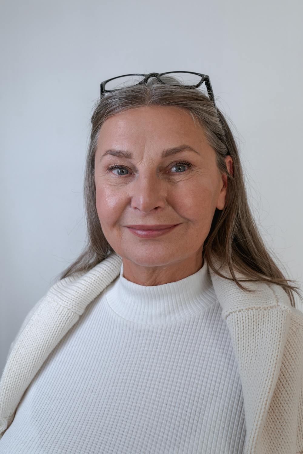 A smiling woman wearing a white sweater ⏐ Source: Pexels