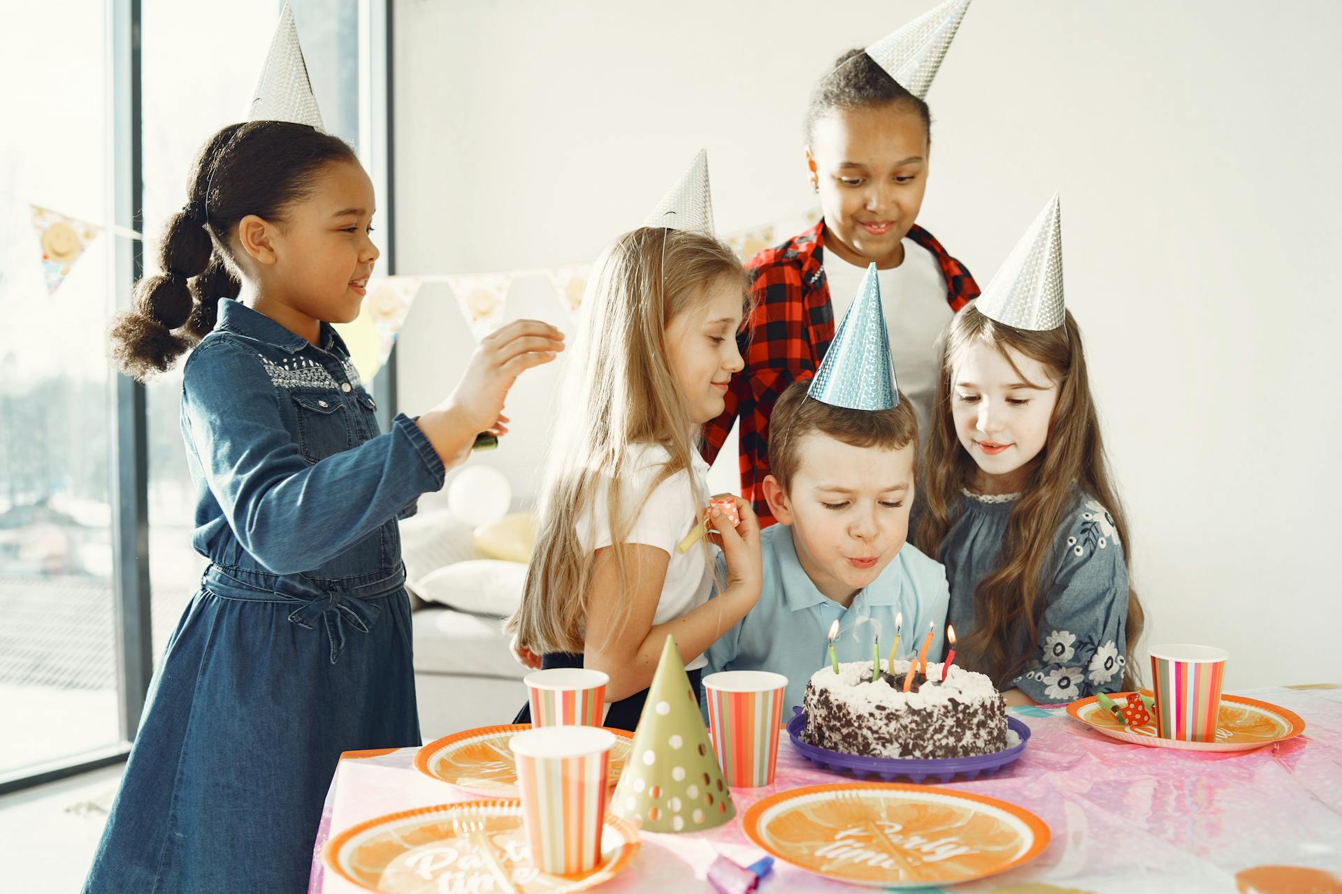 A boy blowing the candles on his birthday cake as delighted children surround him | Source: Pexels