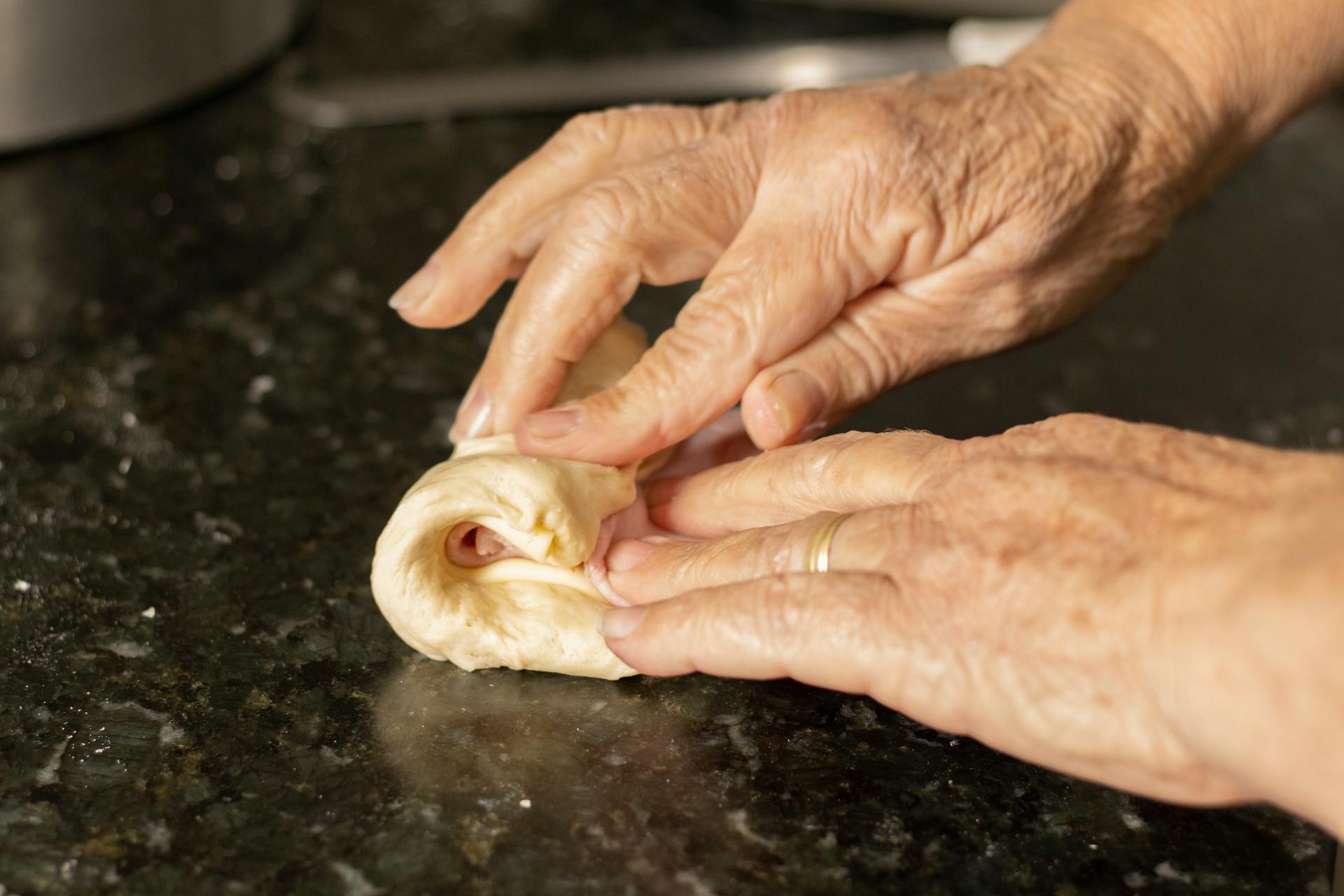 A close-up shot of a woman's hands folding a piece of soft dough | Source: Pexels