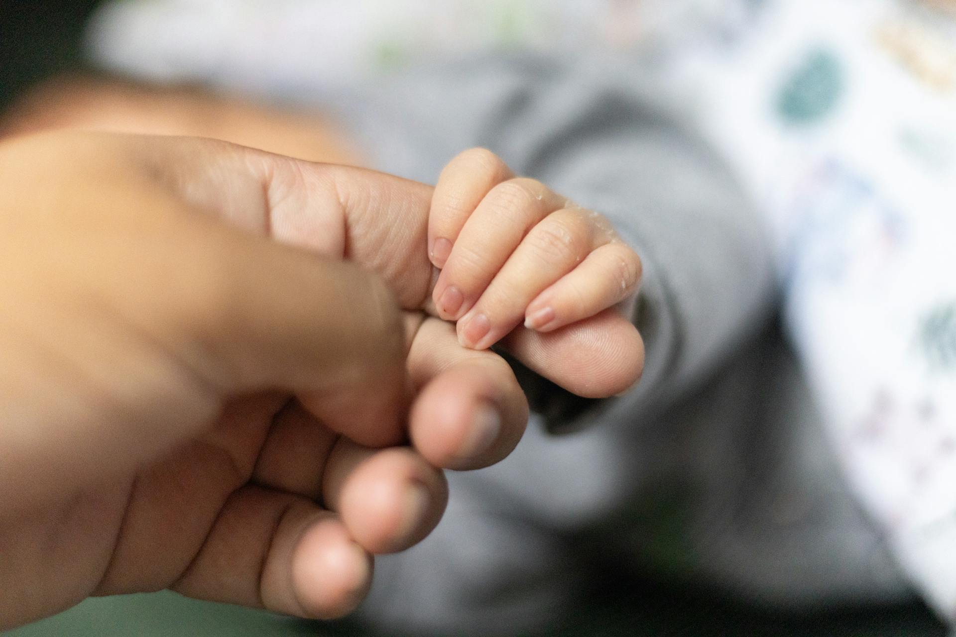 A baby holding a man's finger | Source: Pexels