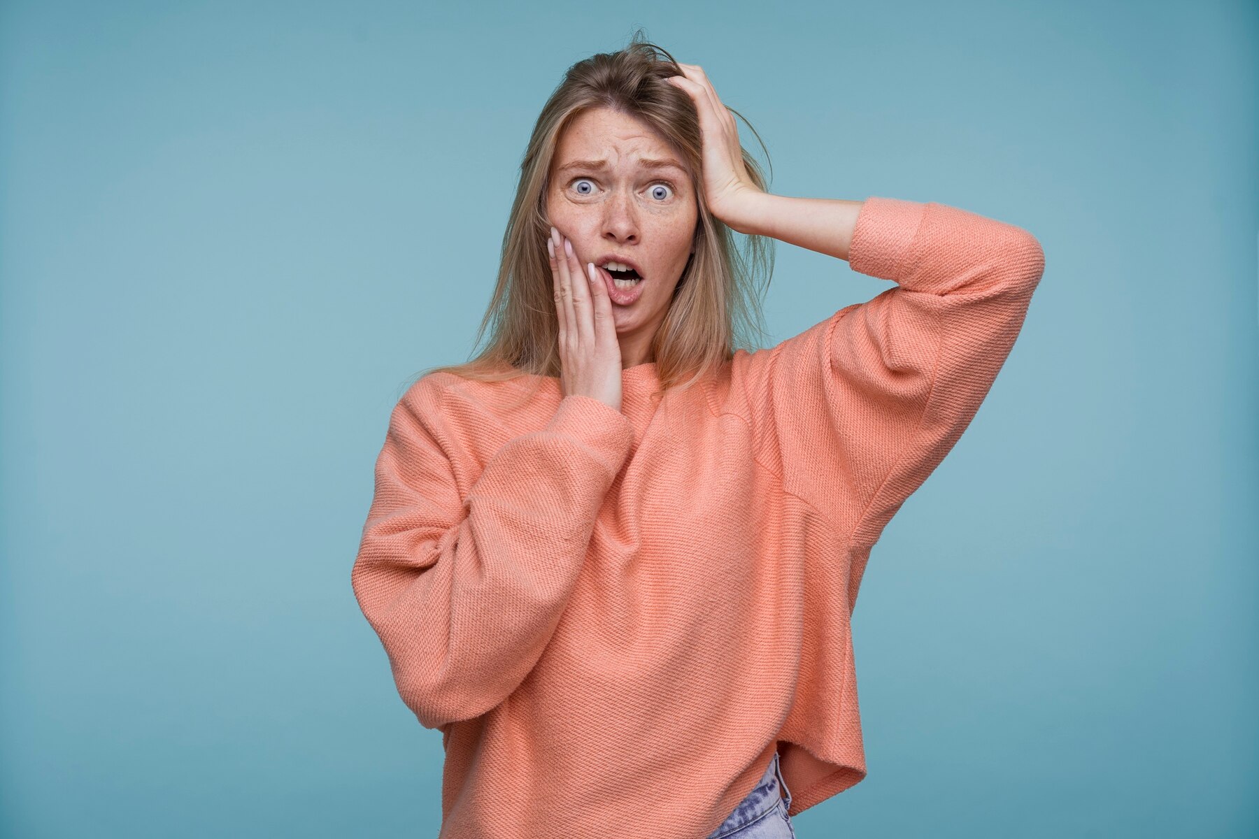 A shocked woman clutching her head | Source: Freepik