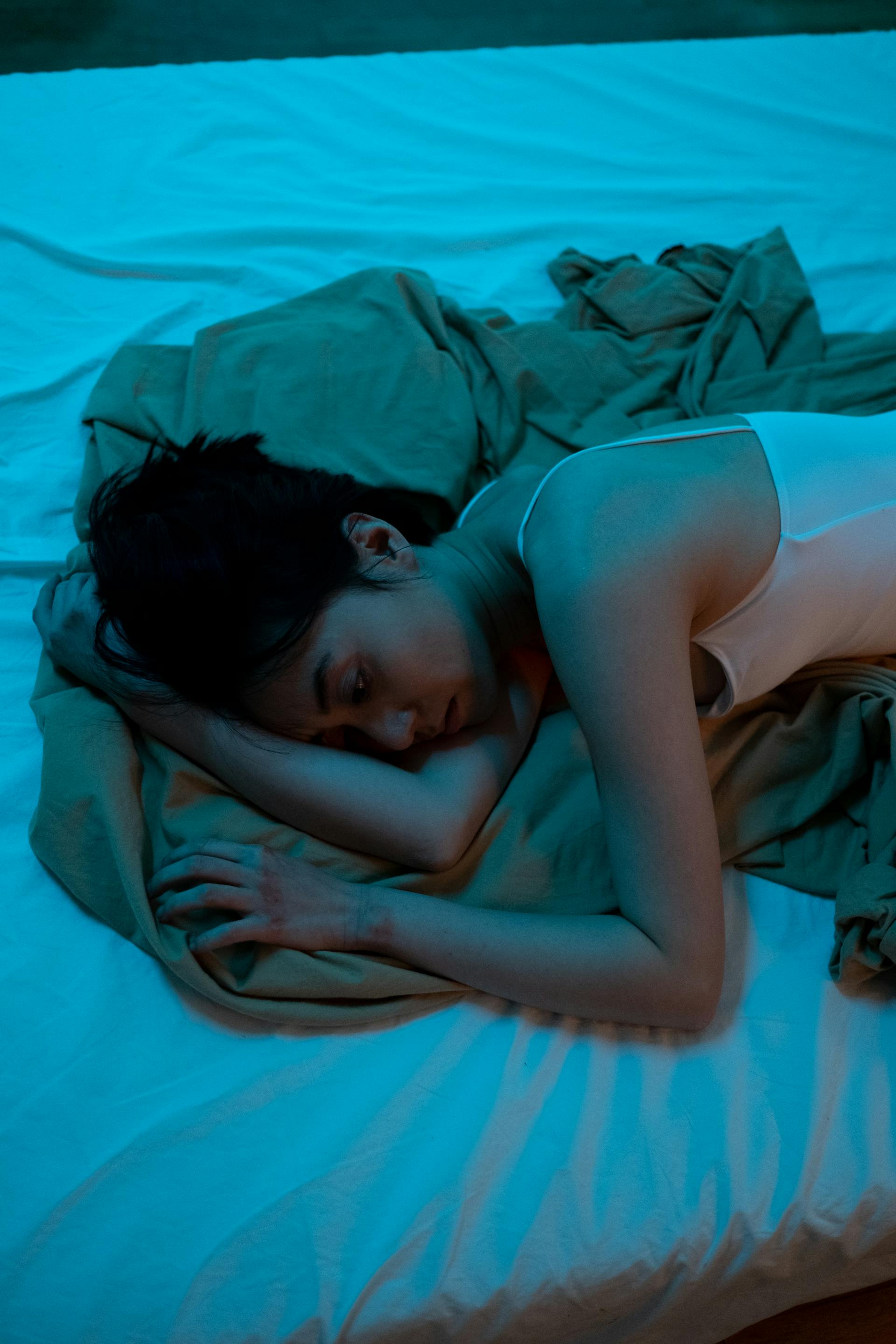 A sad woman lying on a bed | Source: Pexels