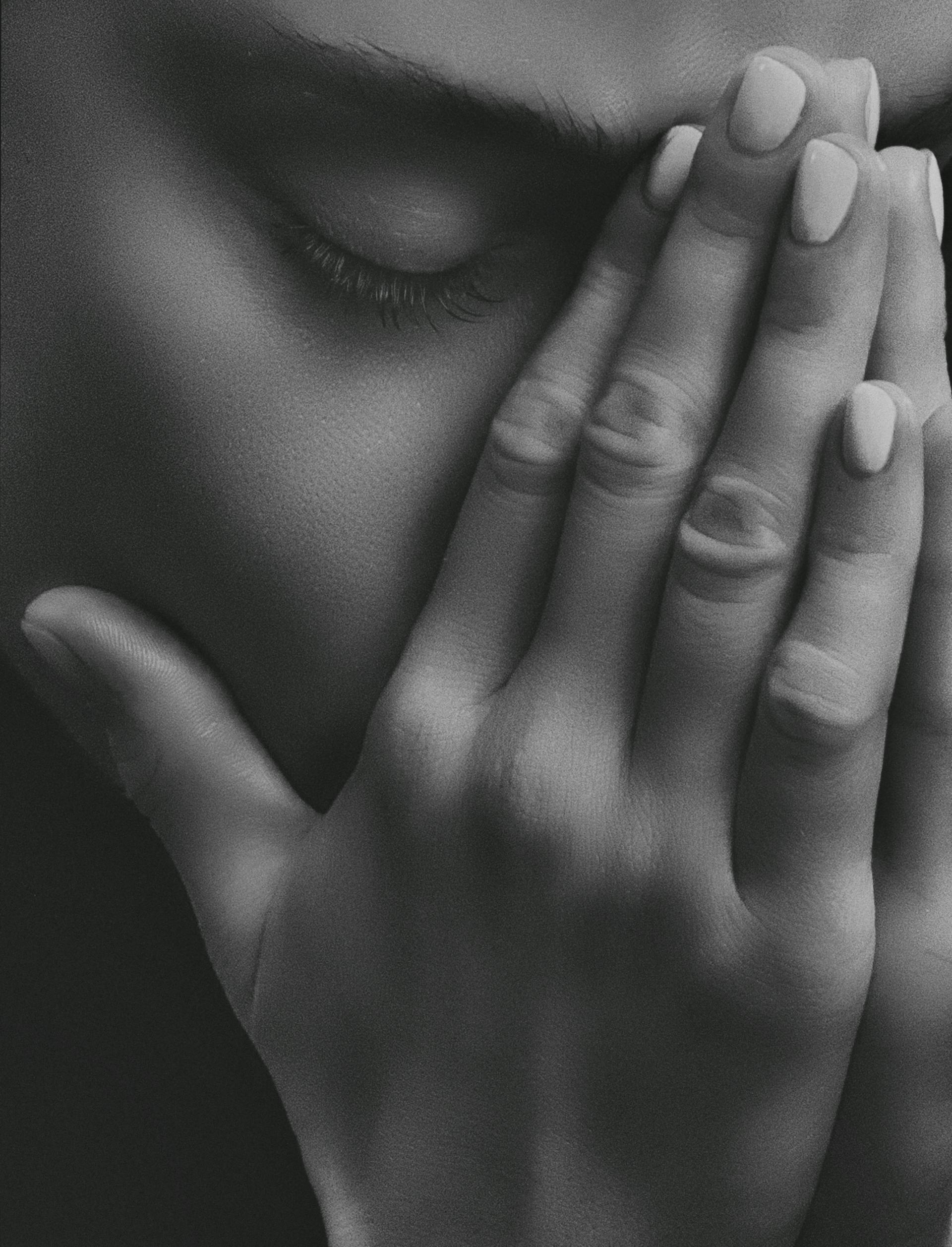 A grayscale close-up shot of a sad woman covering her face with her hands | Source: Pexels