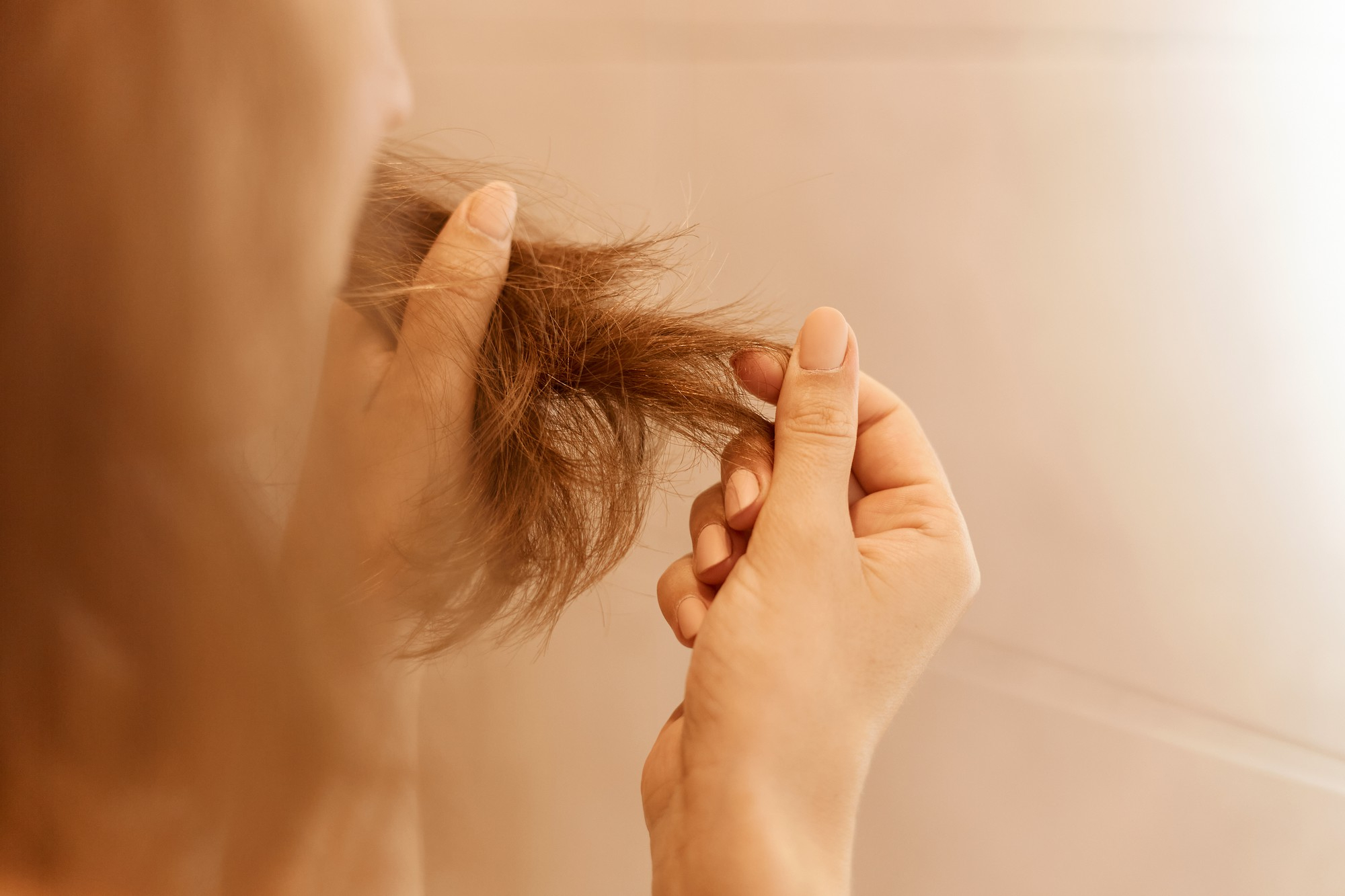A woman looking at her hair | Source: Freepik