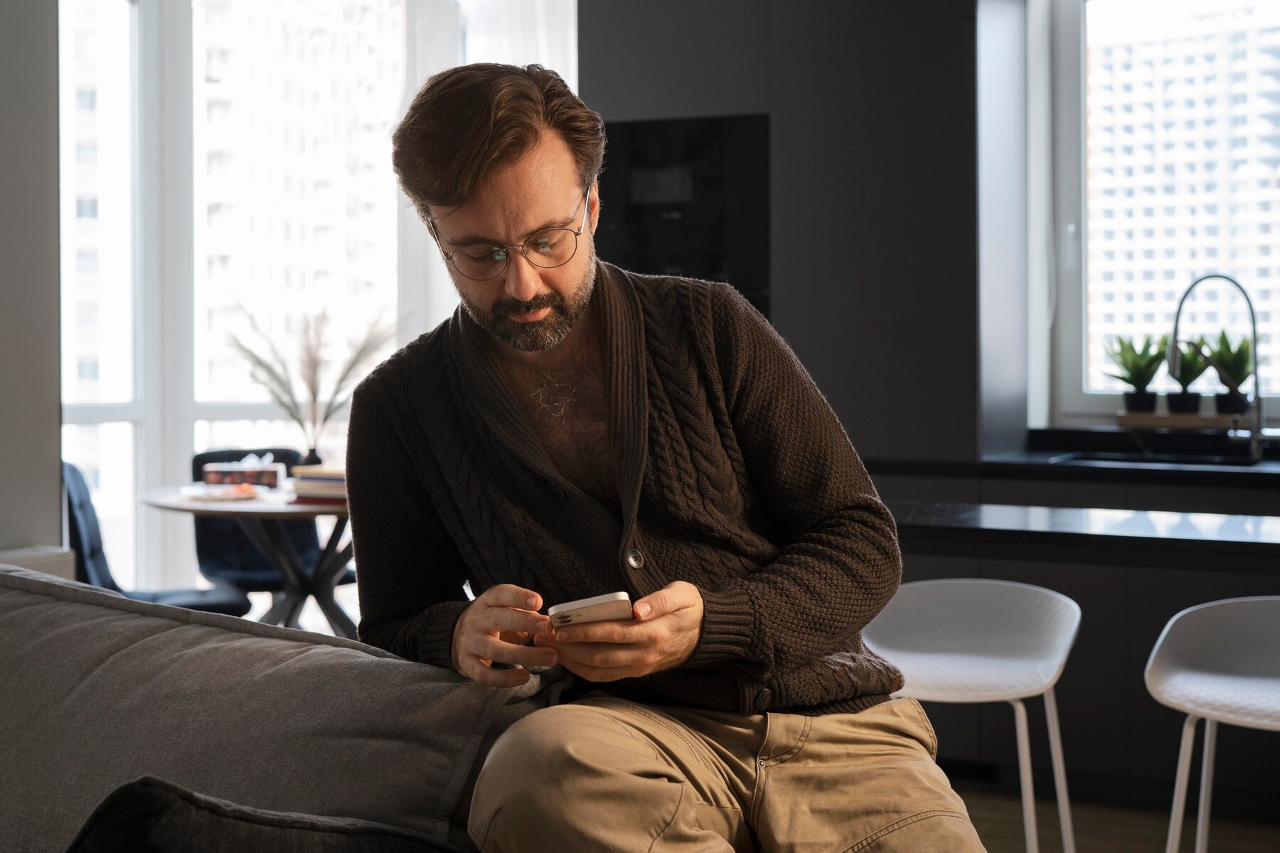 A man on his phone in his living room | Source: Freepik