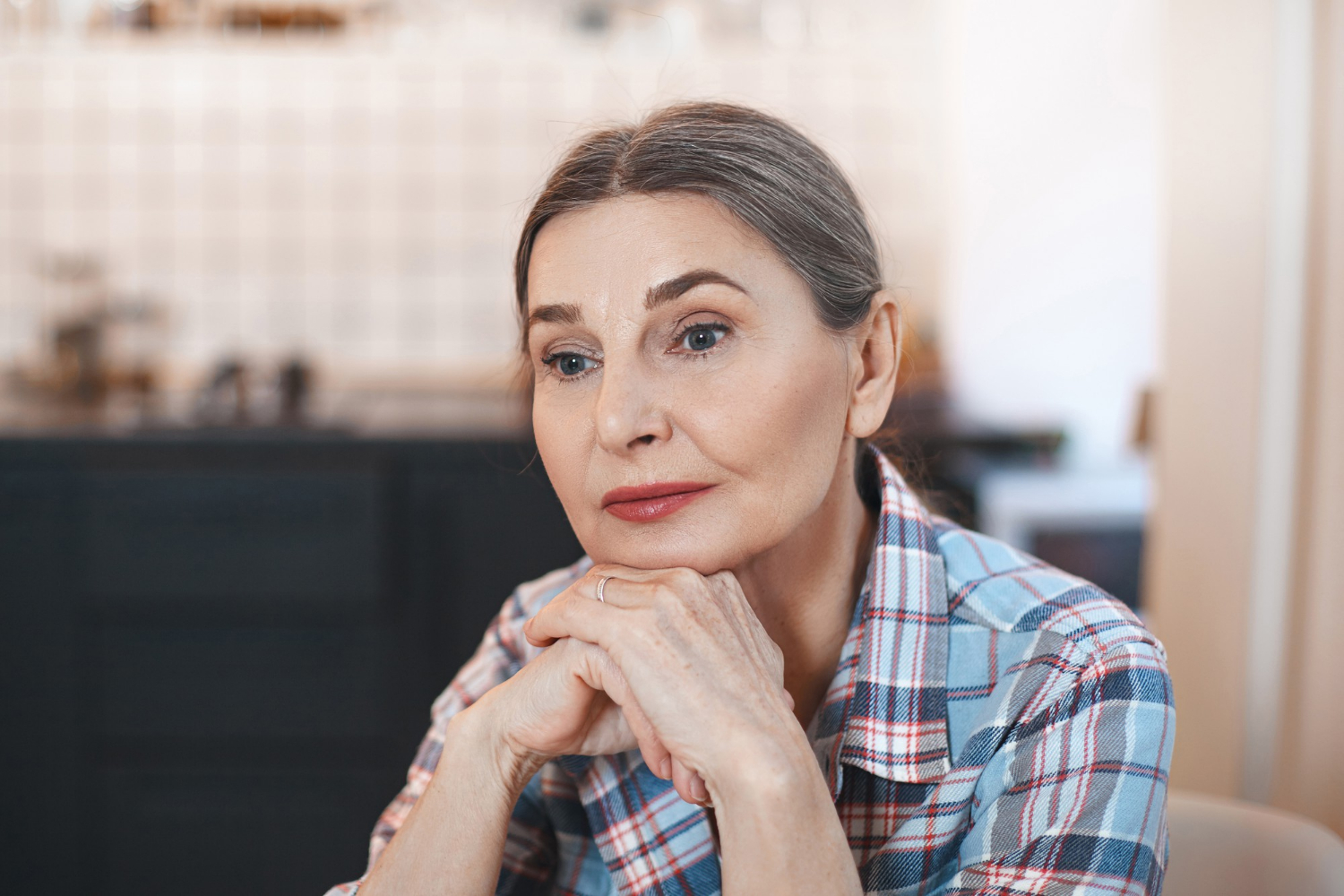 A thoughtful senior woman sitting on a chair | Source: Freepik