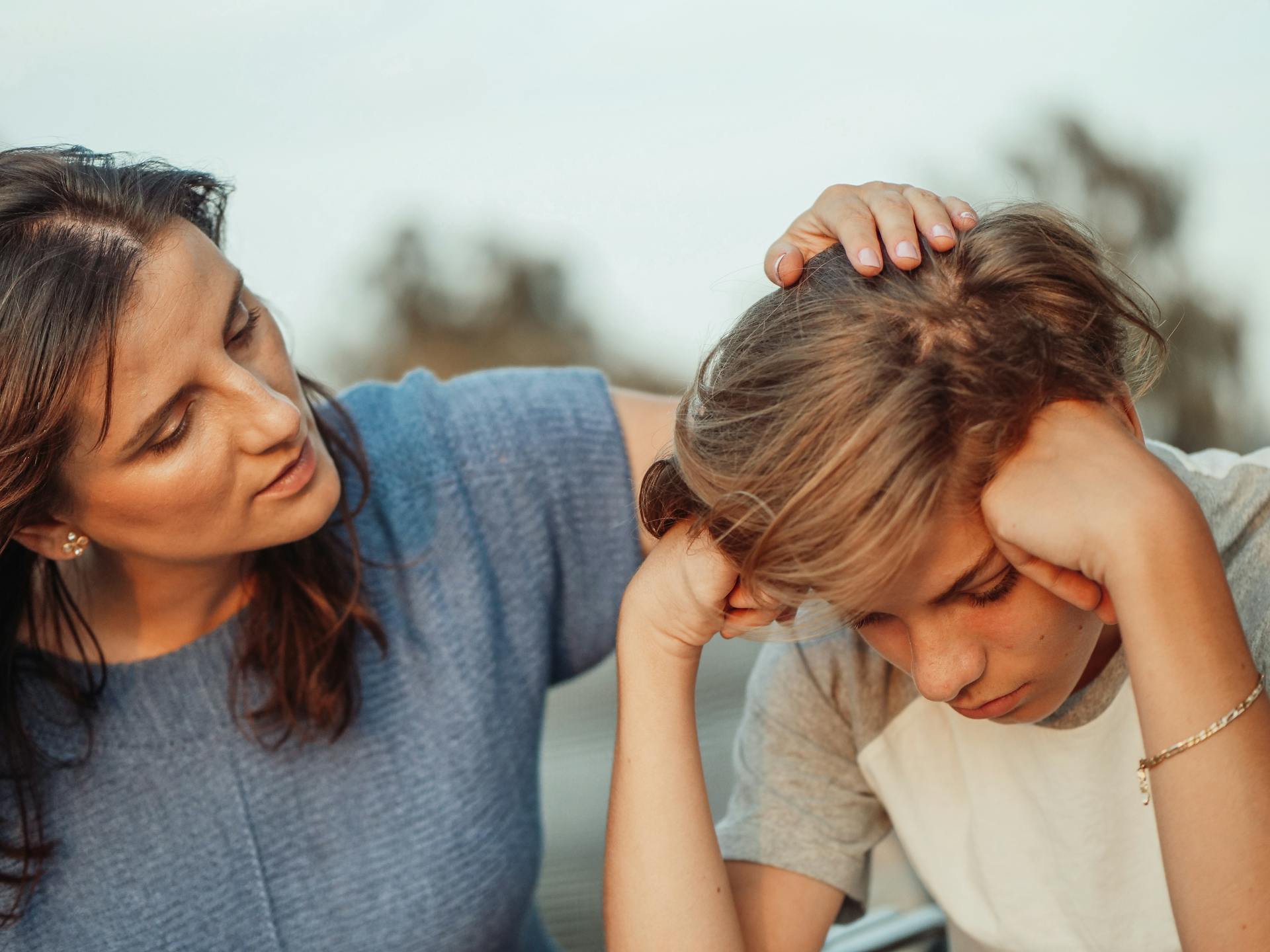 An upset teenager comforted by his mother | Source: Pexels
