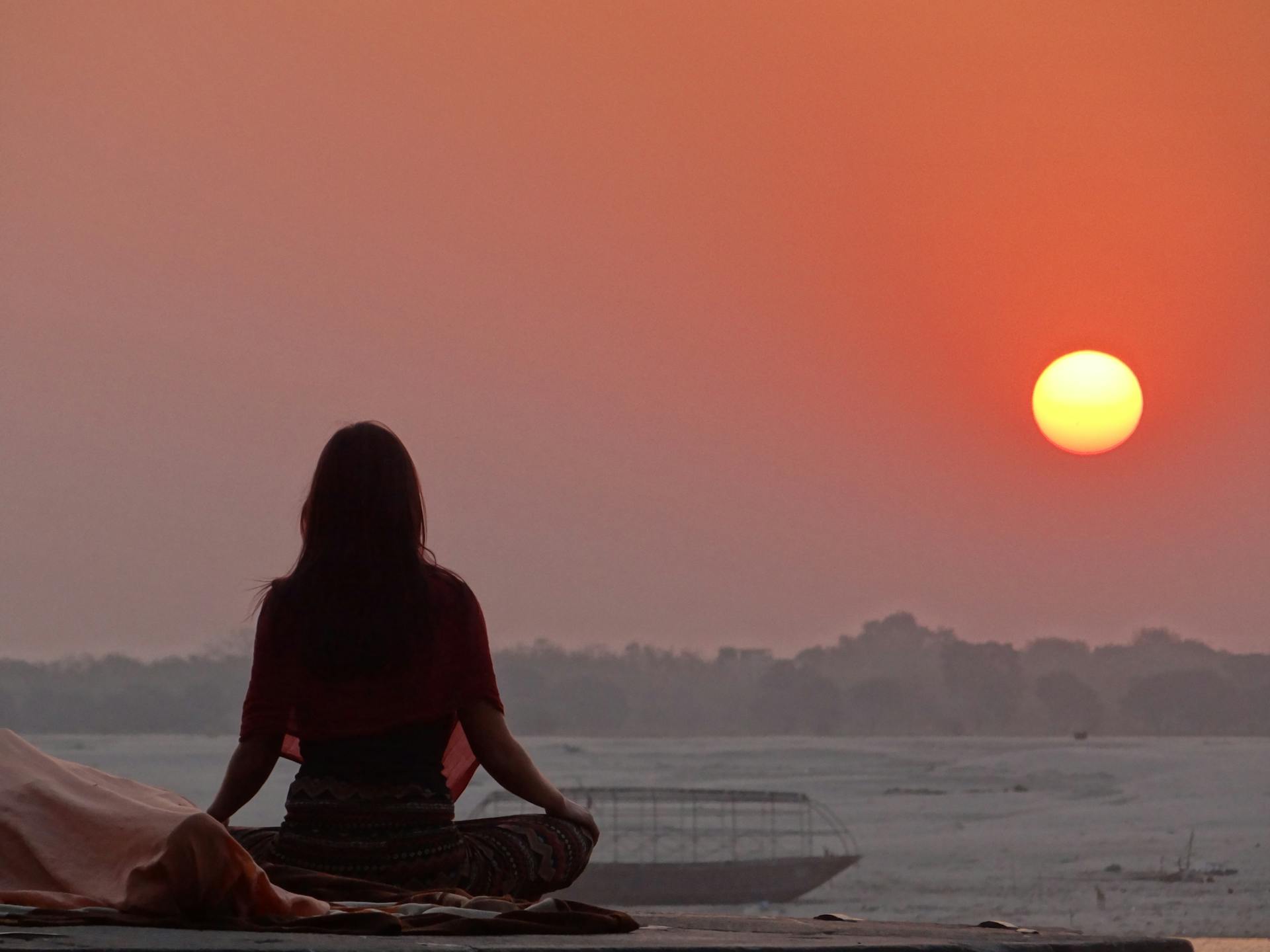 A woman meditating near the sea at sunset | Source: Pexels