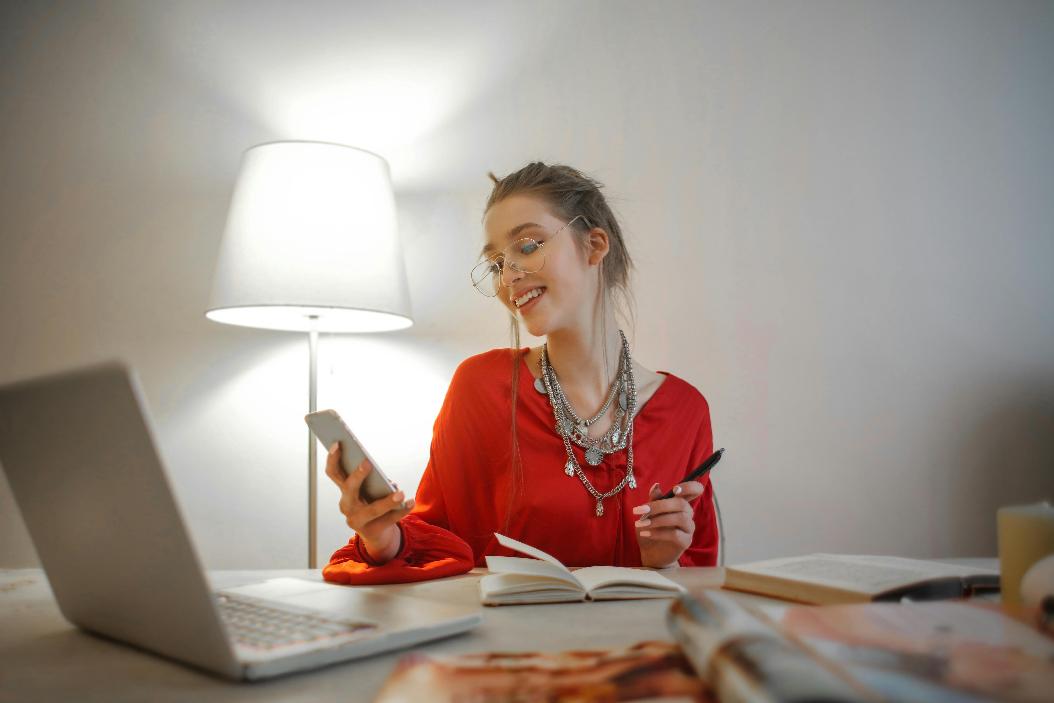 A woman smiling while holding a cellphone | Source: Pexels