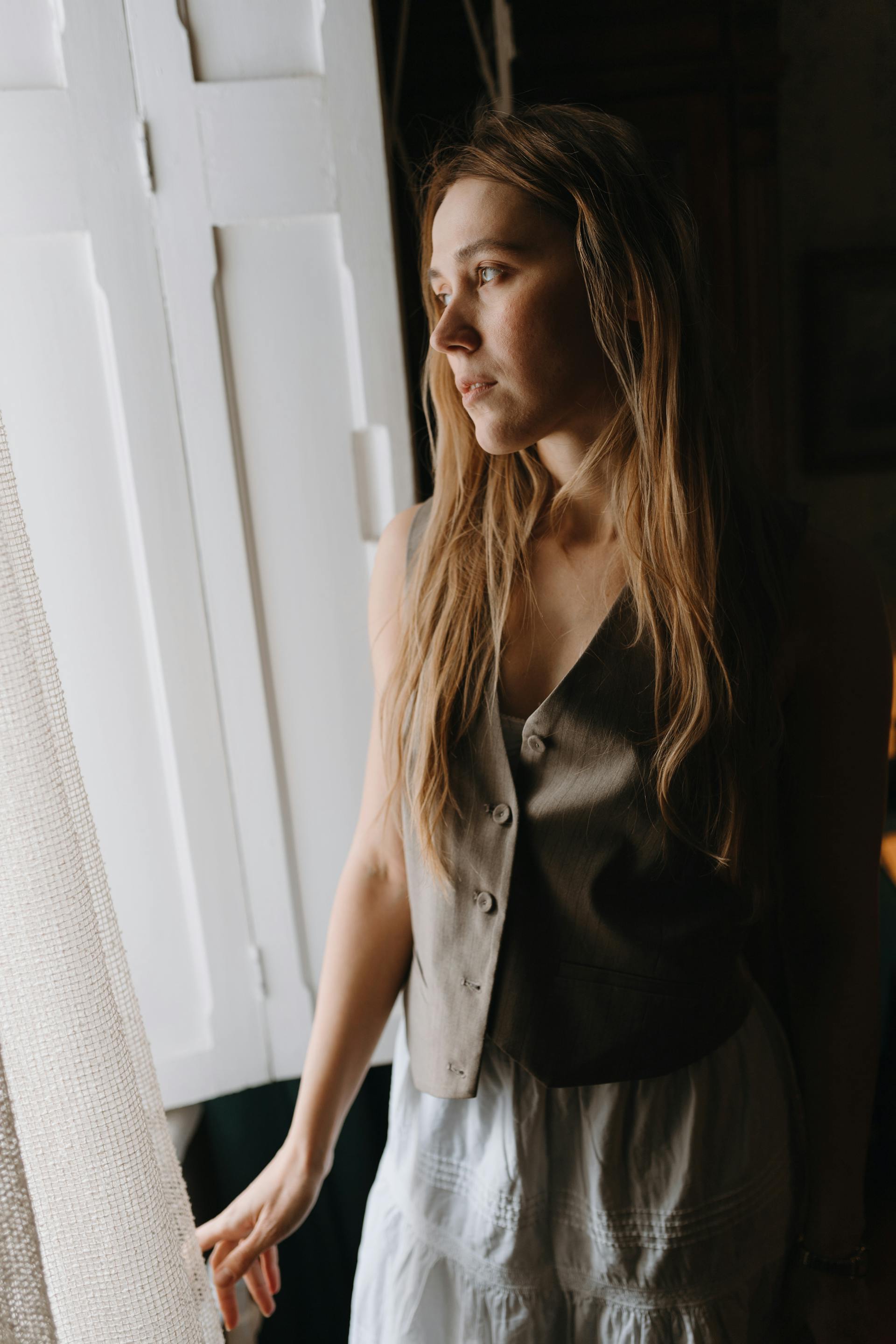 A woman standing by the window in a room | Source: Pexels