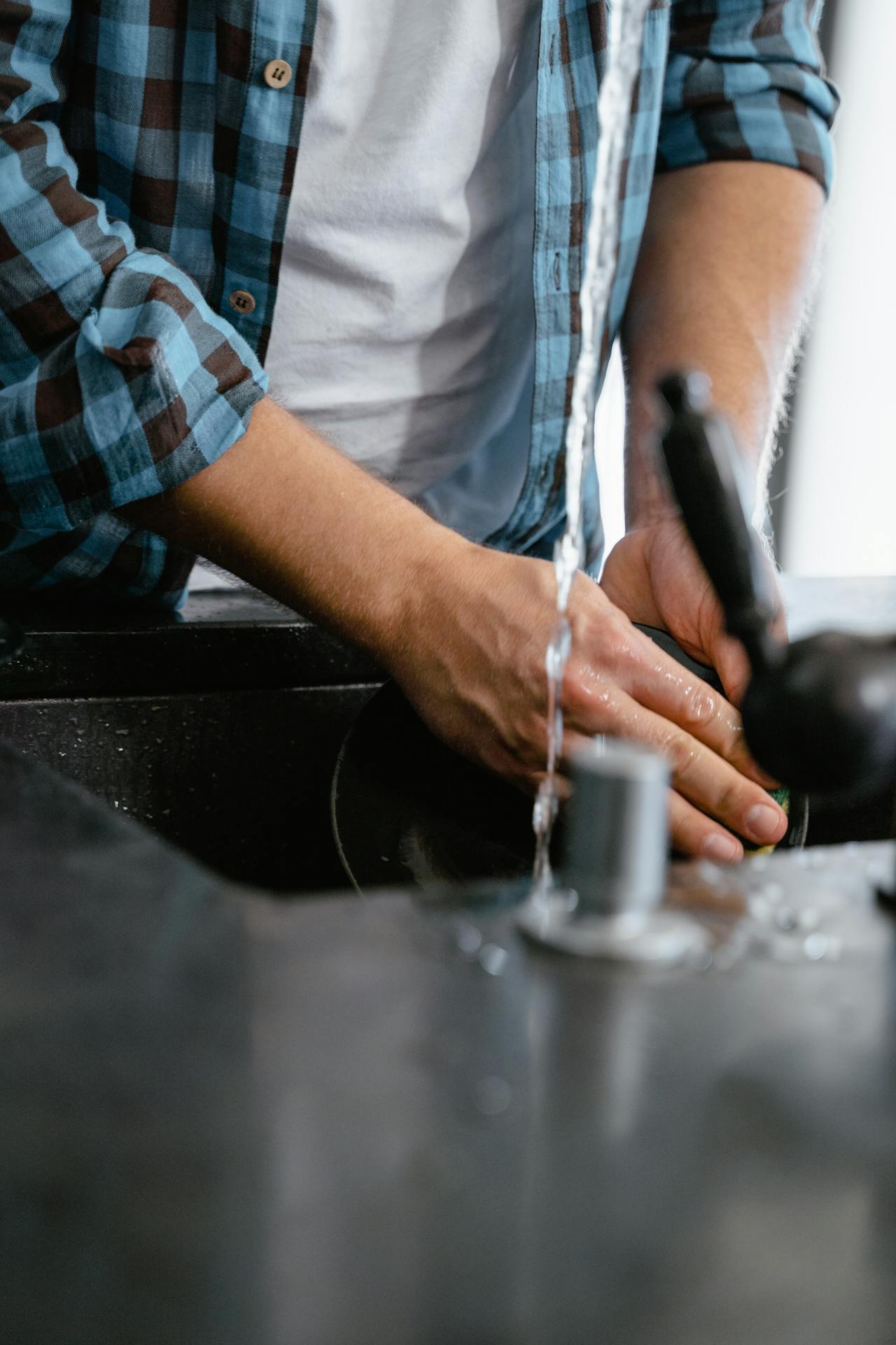 Cropped shot of a man washing a plate | Source: Pexels