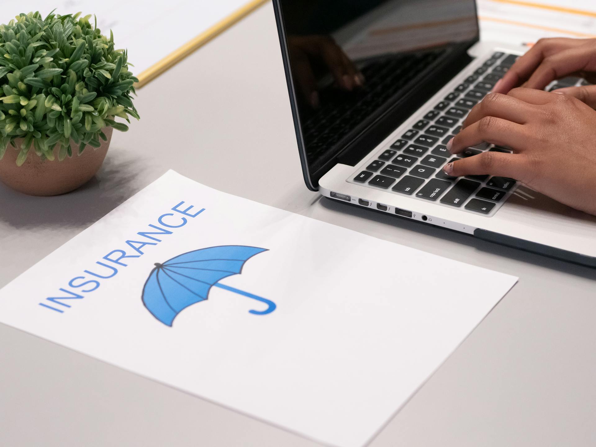 A sheet of paper beside a person typing on a laptop | Source: Pexels