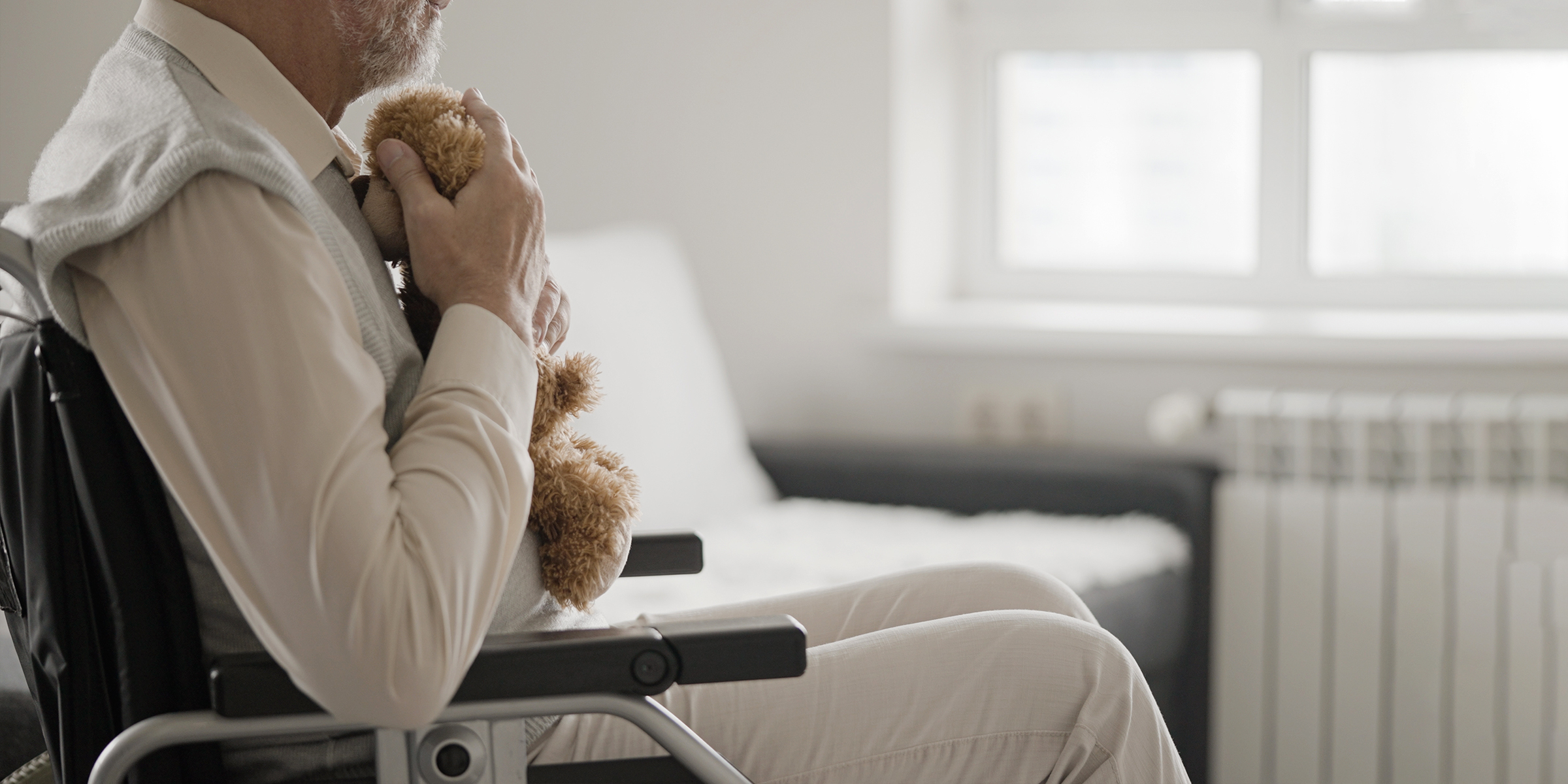 Elderly man sitting in wheelchair with a teddy bear | Source: Shutterstock