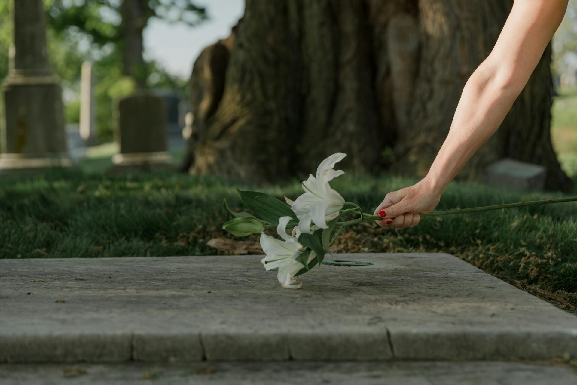 A woman putting flowers on a grave | Source: Pexels