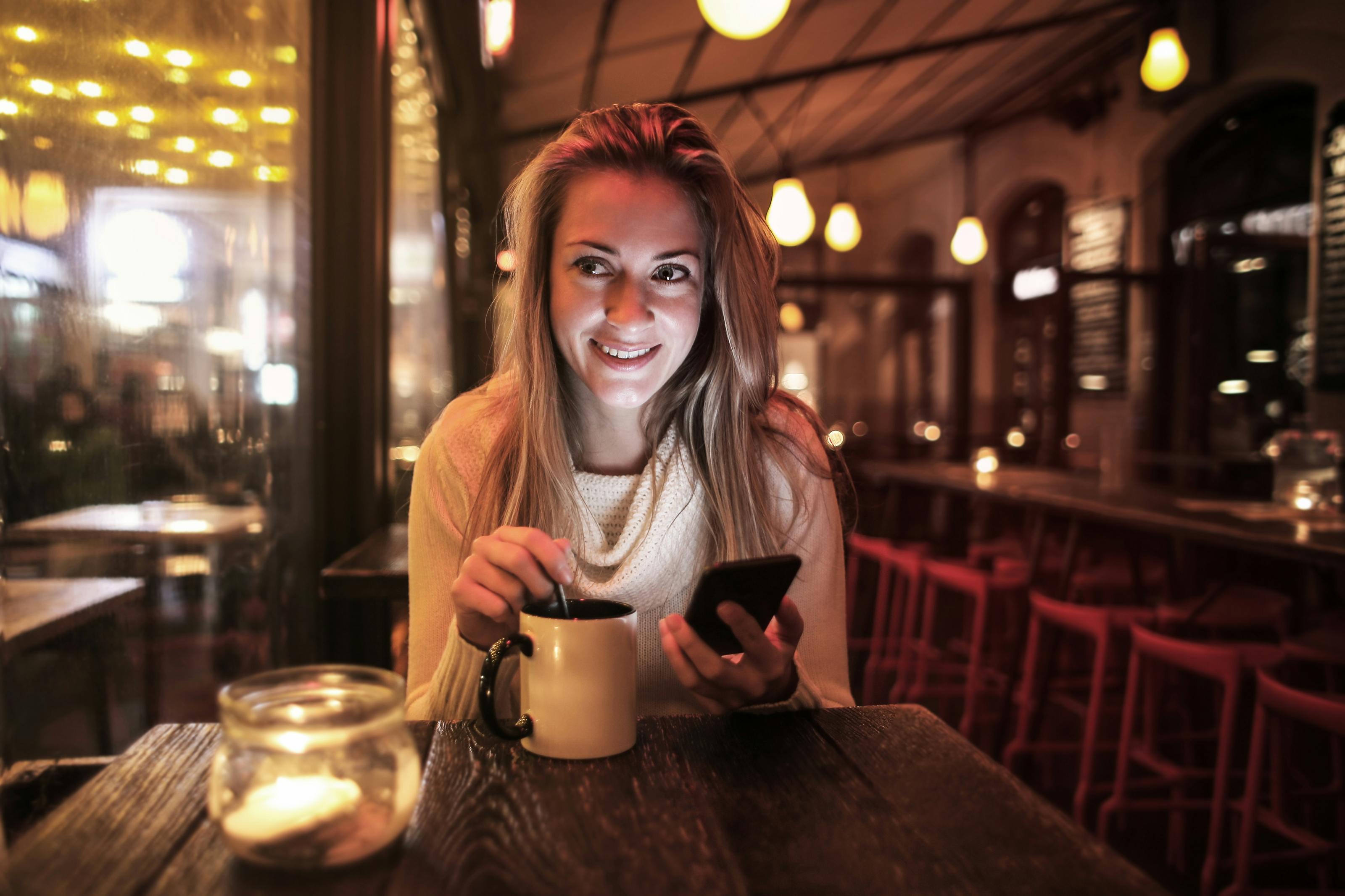 A woman holding her phone in a cafe | Source: Pexels