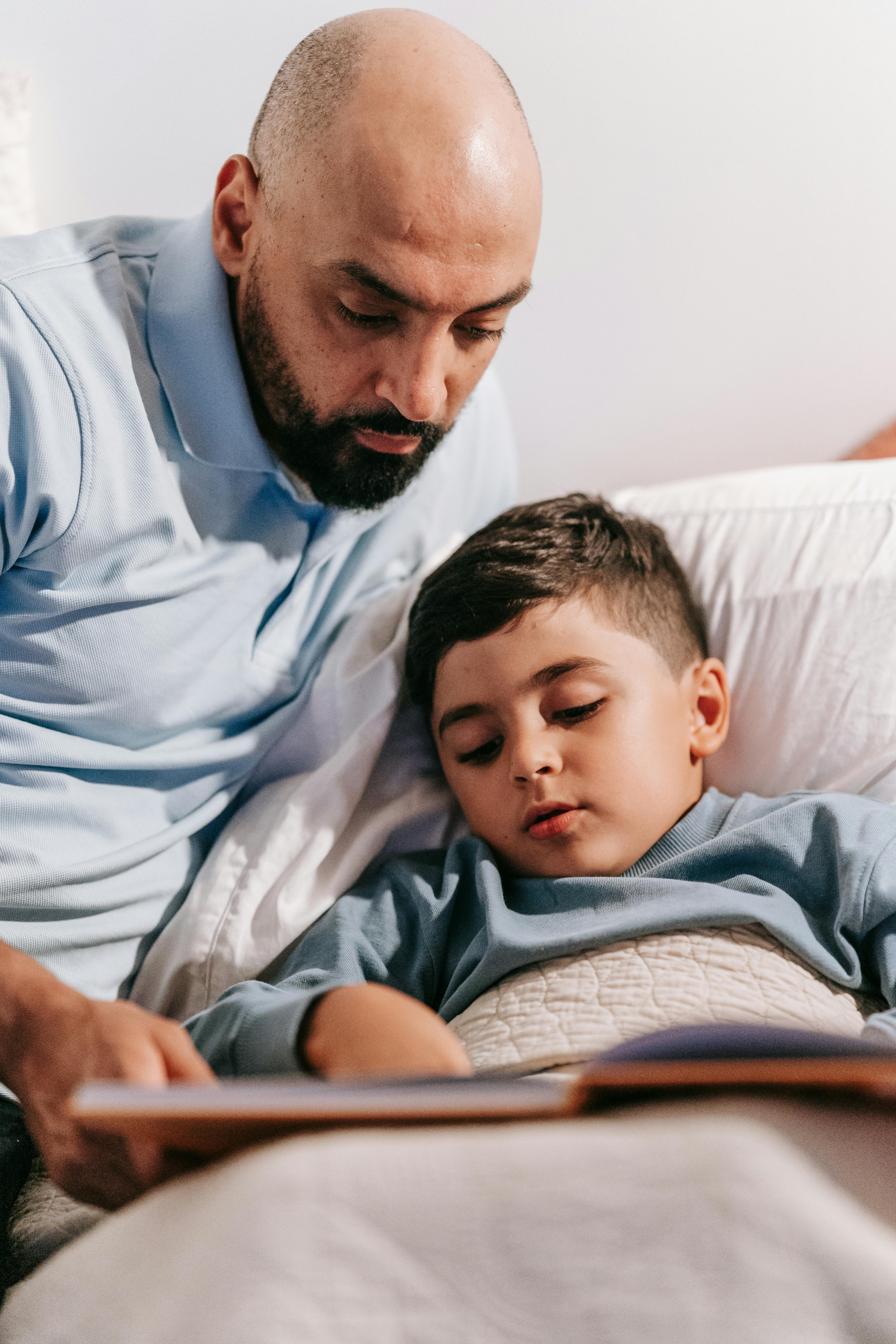 A man reading a bedtime story to his child | Source: Pexels