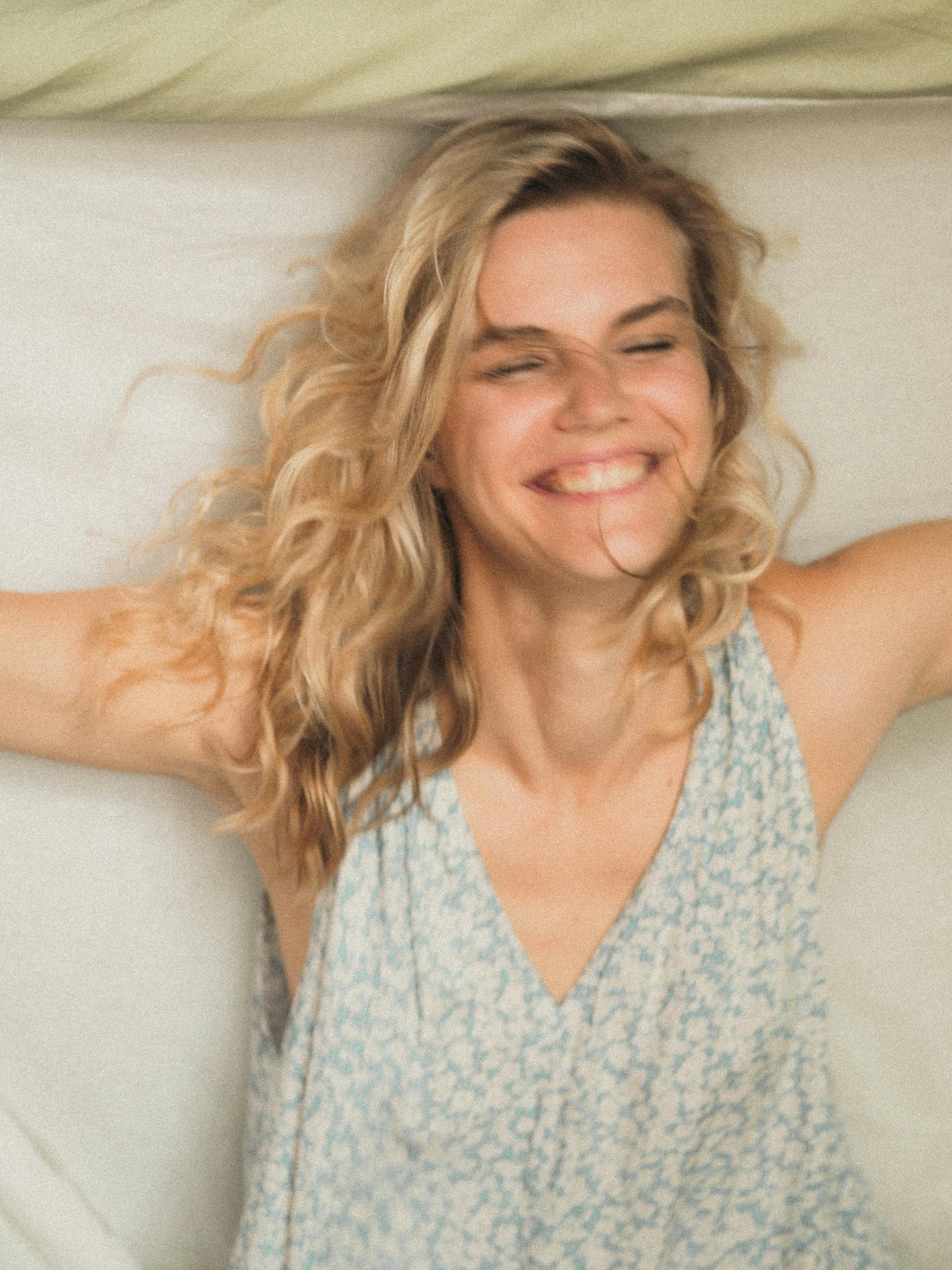 A woman lying on a bed laughing | Source: Pexels
