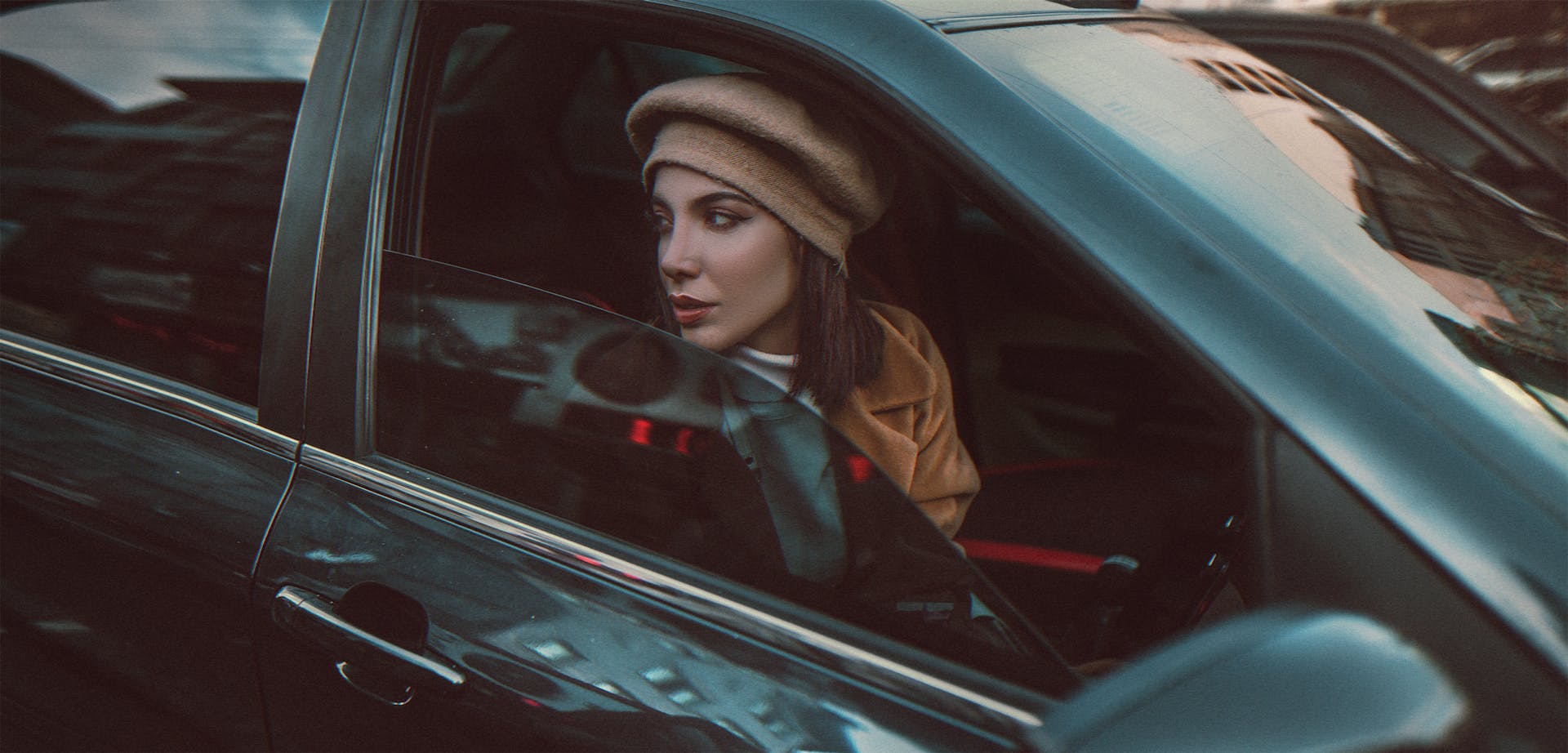 A woman in a beret and a brown coat looking out the window of a car | Source: Pexels