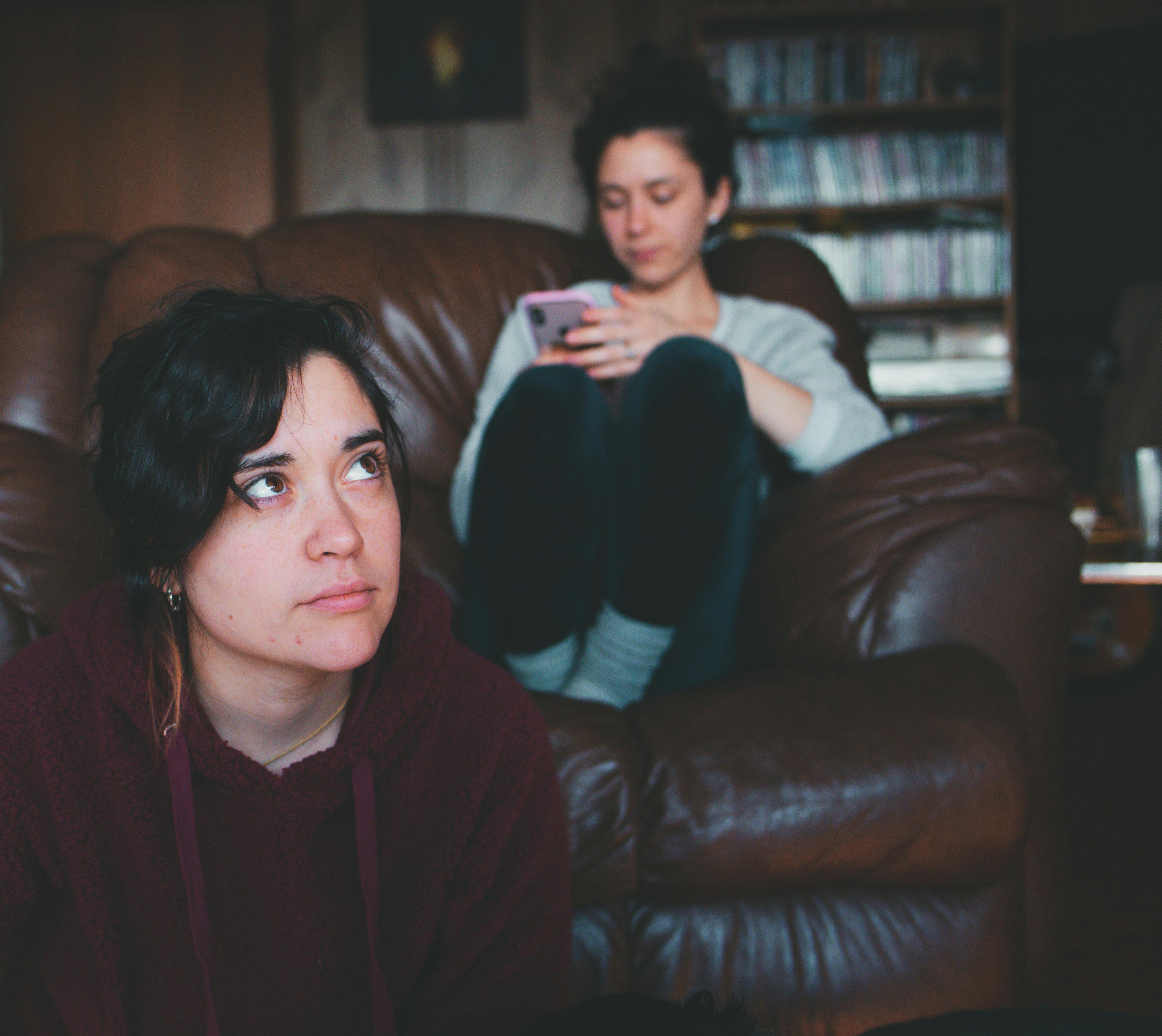 One woman sitting on the floor while another sits on the couch | Source: Pexels