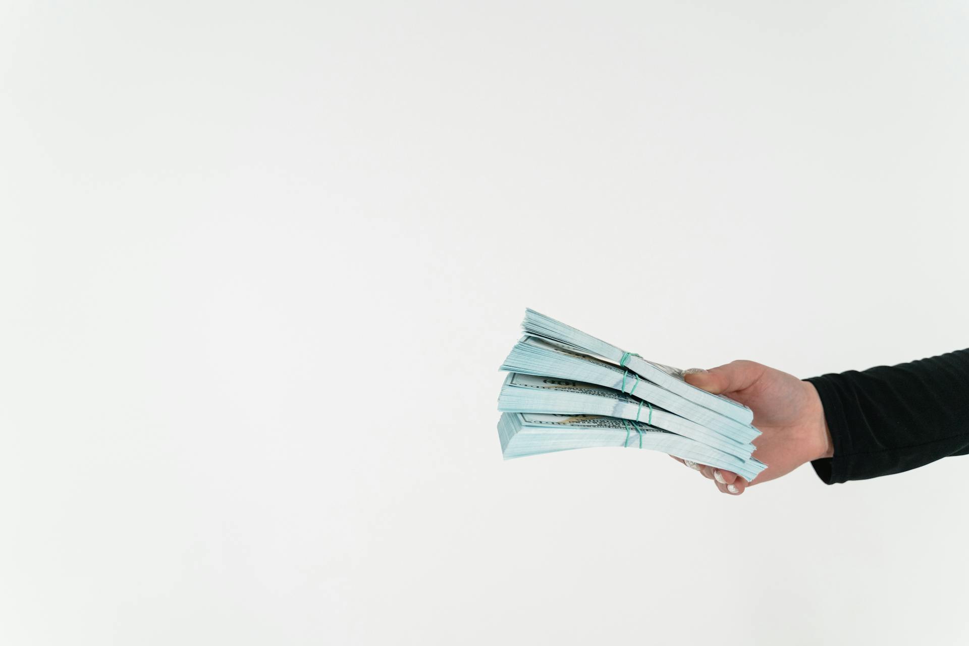 Close-up cropped shot of a person holding wads of money | Source: Pexels